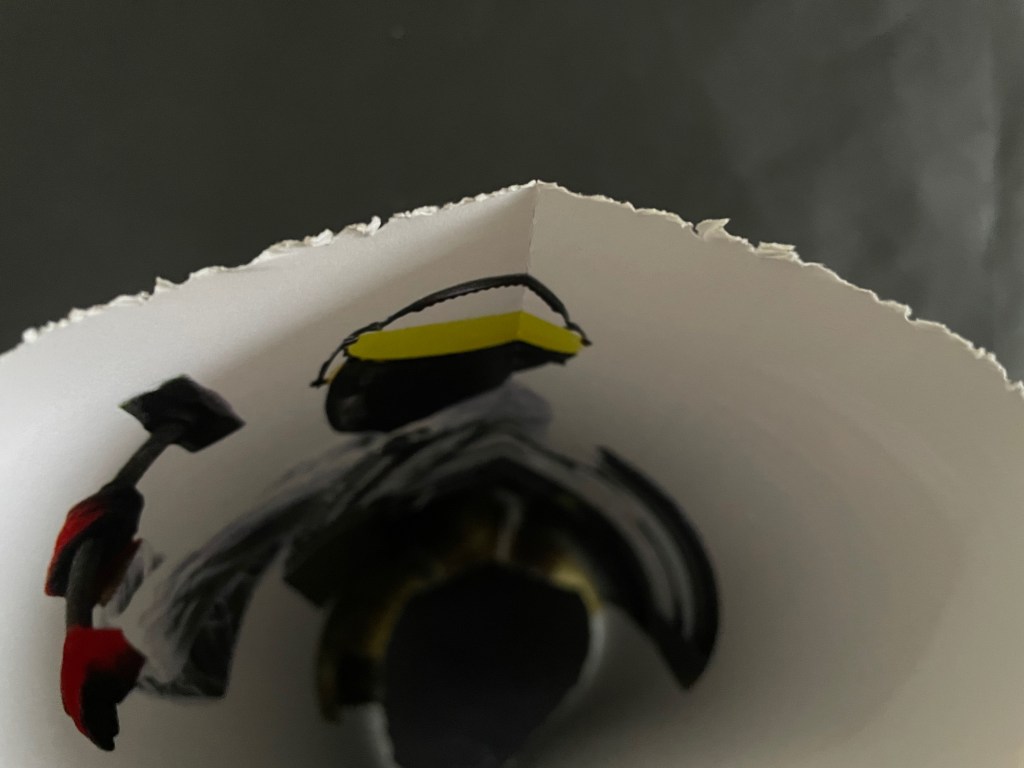 A close-up view of a torn paper edge with a black and yellow illustration of a person holding a hammer.