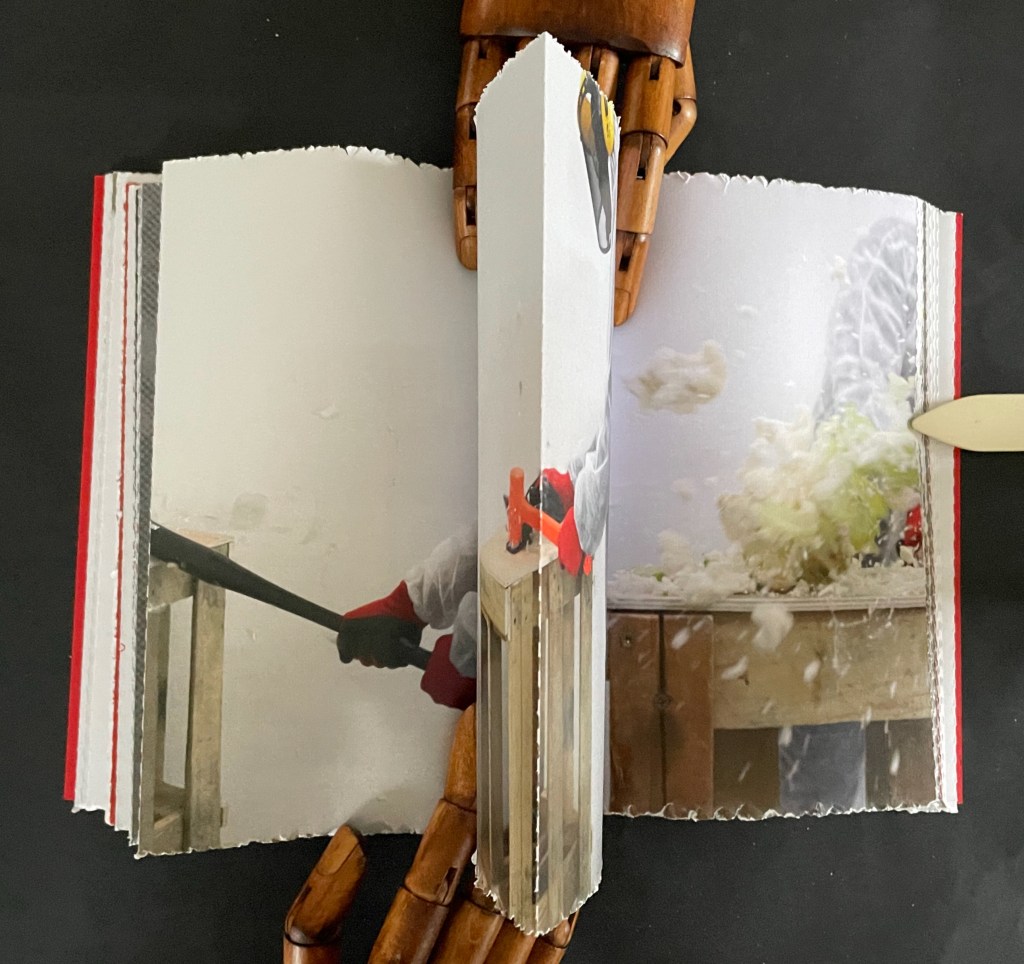 An open book with a blurred image of a person using a tool on one page and a motion shot of lettuce being processed on the opposite page. The background features a wooden table and a textured surface.
