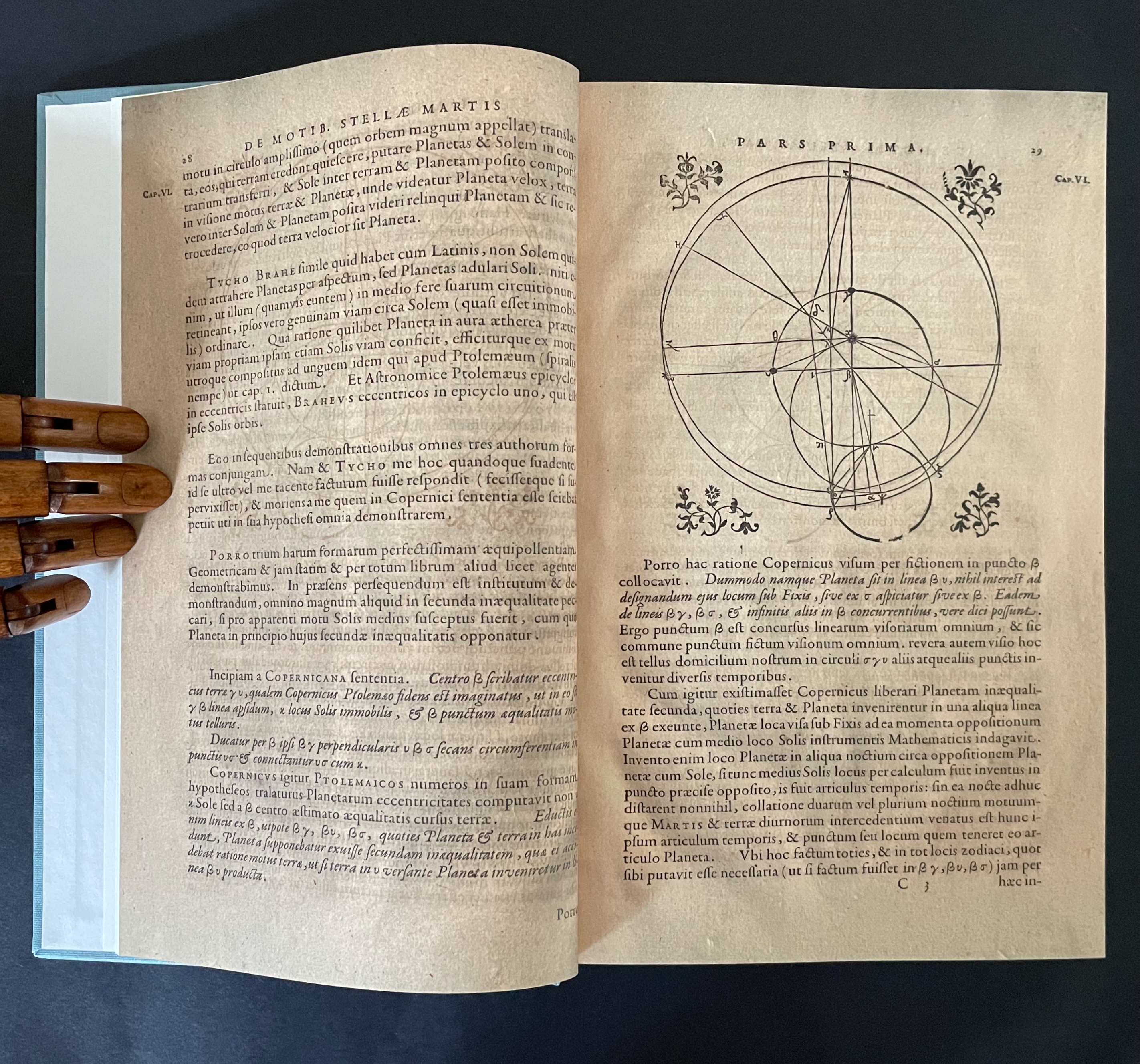 An open historical book page featuring Latin text and a diagram illustrating celestial motions and planetary orbits.