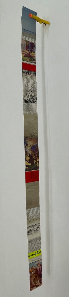 A vertical art installation featuring a scrolling strip of images and text, with various illustrations and colorful sections, displayed on a wall.