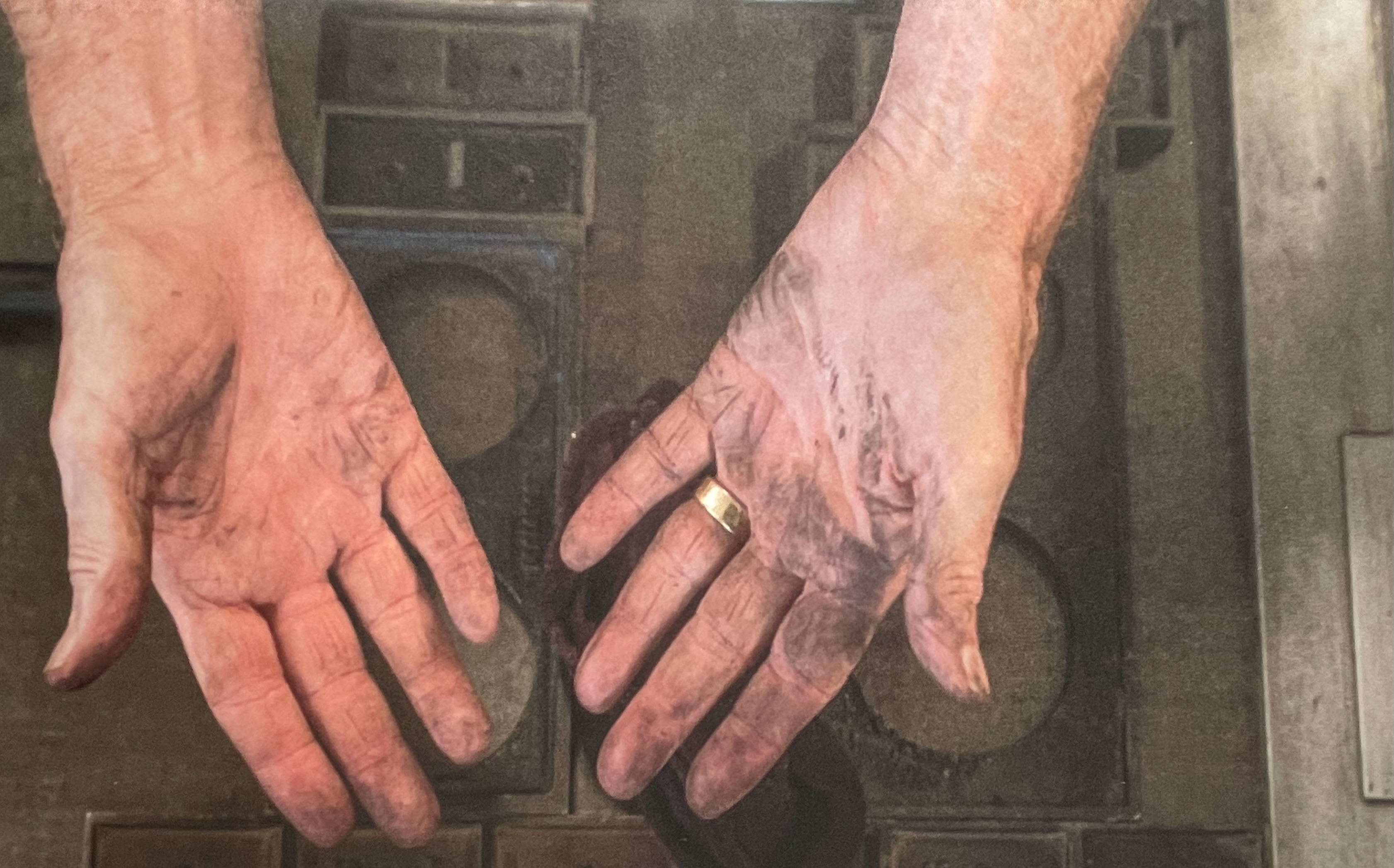 Close-up of two hands with visible dirt and wear, one wearing a gold ring.