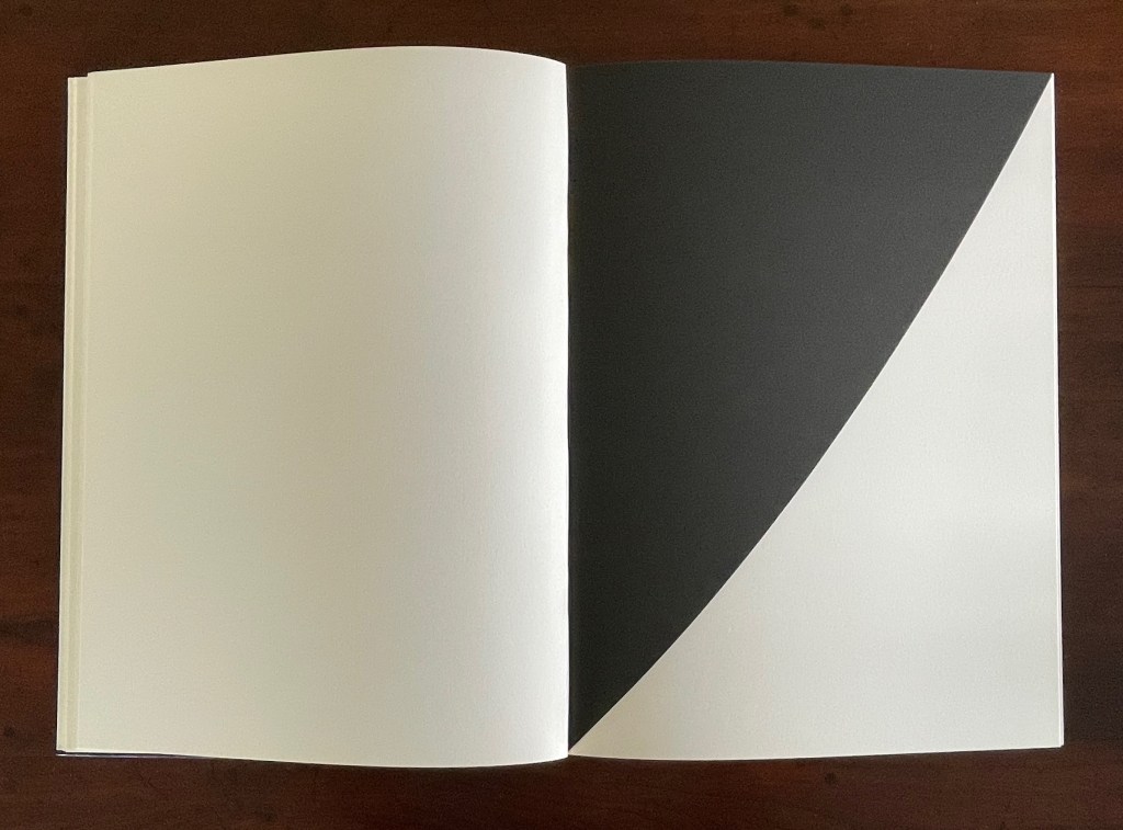 An open book displaying a blank left page and a right page featuring a black triangular shape on a white background.