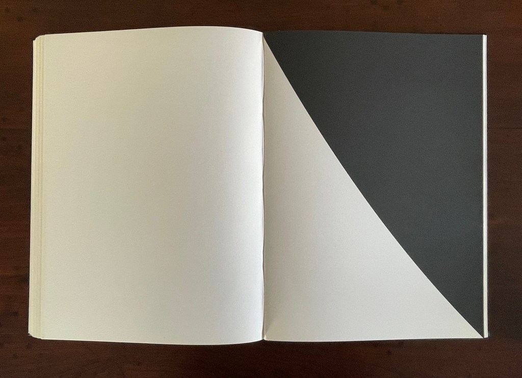 A blank book opened to show two pages, one side white and the other featuring a diagonal black section.