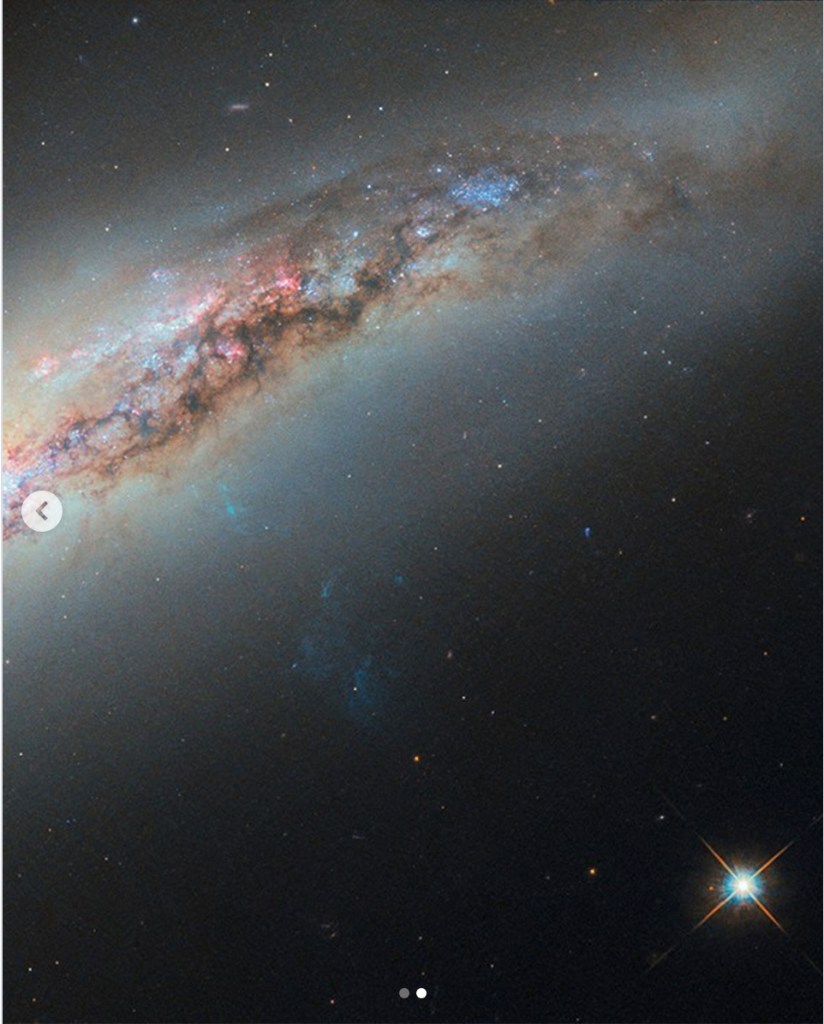 A cosmic image showcasing a spiral galaxy with vibrant blue and pink star formations, surrounded by a dark expanse of space filled with distant stars.
