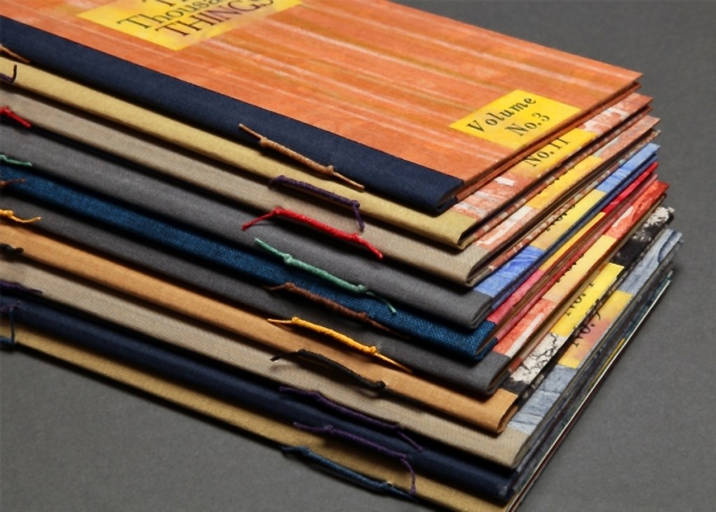 A stack of colorful booklets arranged neatly, displaying various covers with visible titles and volume numbers, resting on a dark surface.