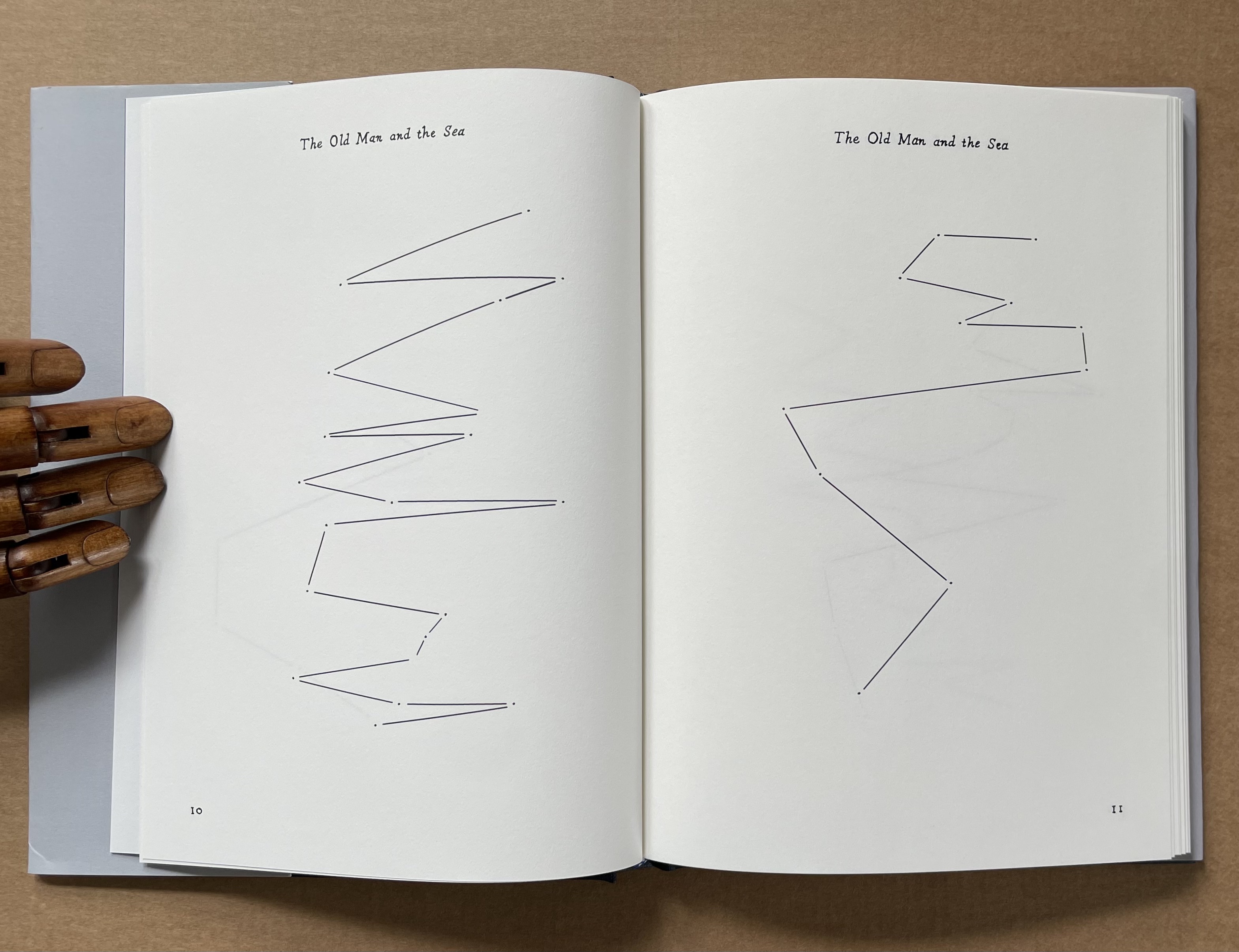 Open book pages featuring abstract line art related to 'The Old Man and the Sea', with a wooden hand holding the pages.