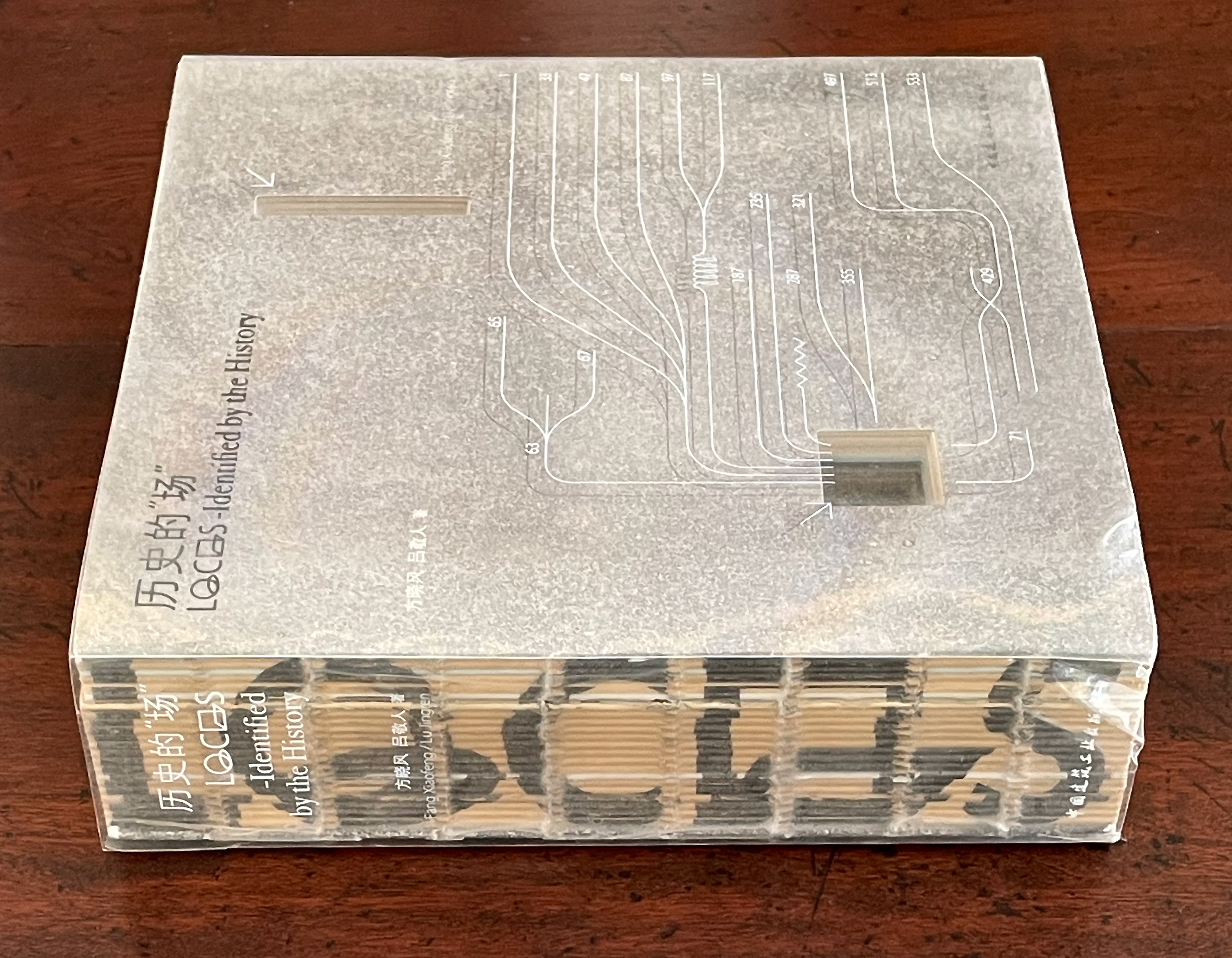 A close-up of a book titled 'Locating - Identified by the History' with a clear plastic cover, showing its spine and decorative elements on the side.