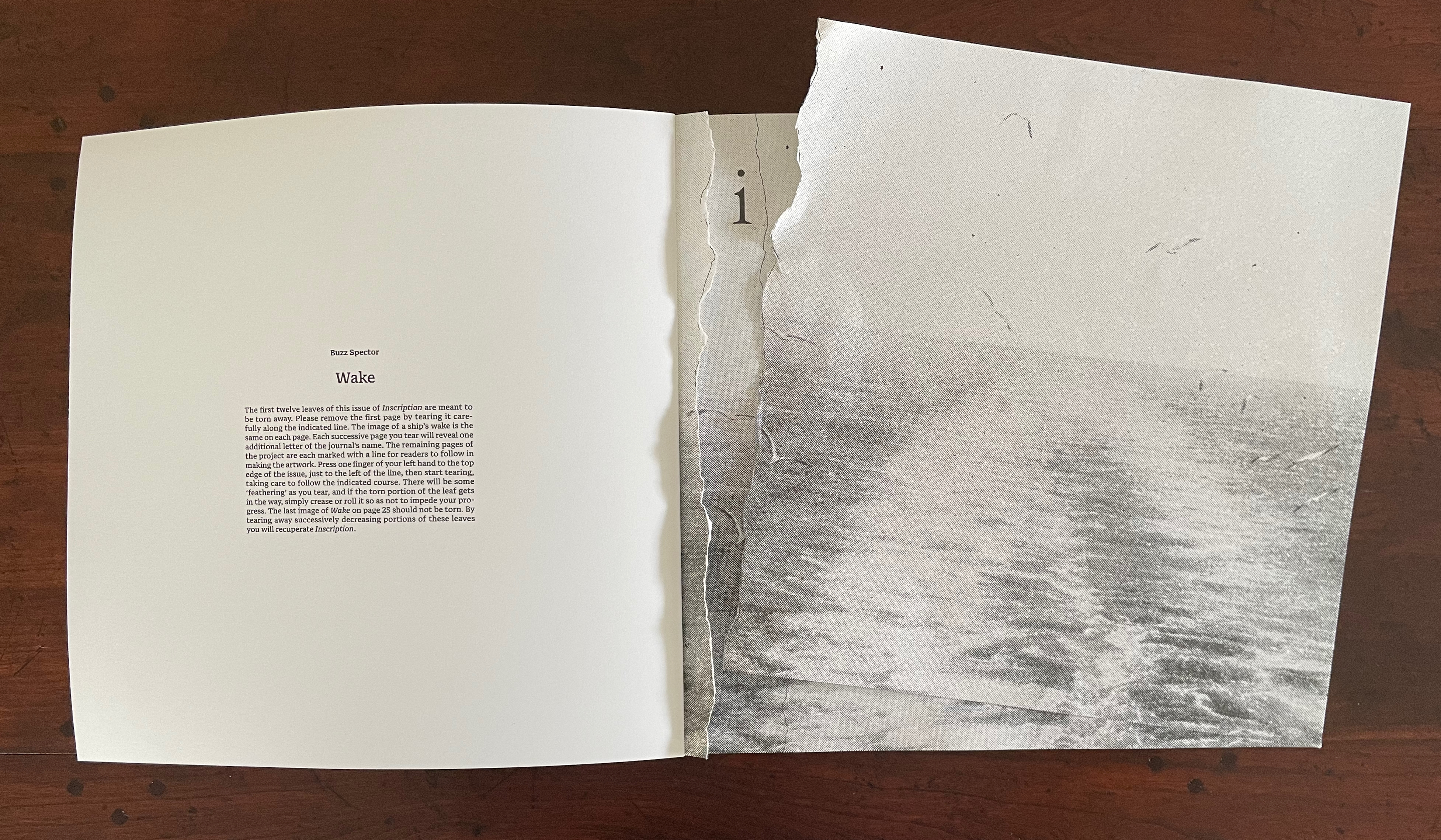 An open book featuring a page titled 'Wake' by Buzz Spector, with a partially torn edge revealing a black and white image of water. The left page includes explanatory text about the book's design.