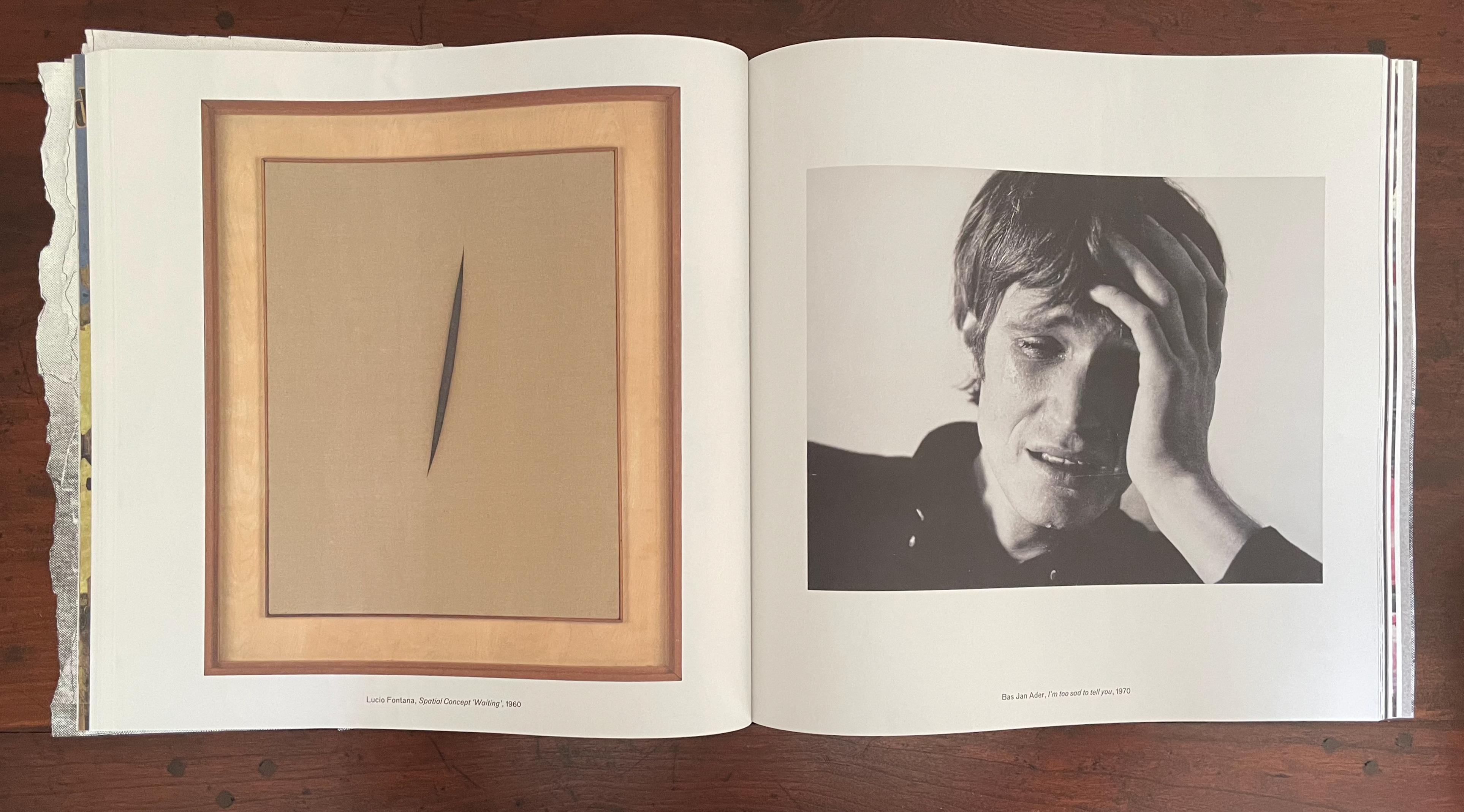 An open book displaying two artworks: on the left, a piece titled 'Spatial Concept Waiting' by Lucio Fontana featuring a slit on a beige canvas, framed in wood; on the right, a black-and-white photograph by Bas Jan Ader titled 'I'm too sad to tell you' depicting a man with a distressed expression, holding his head.