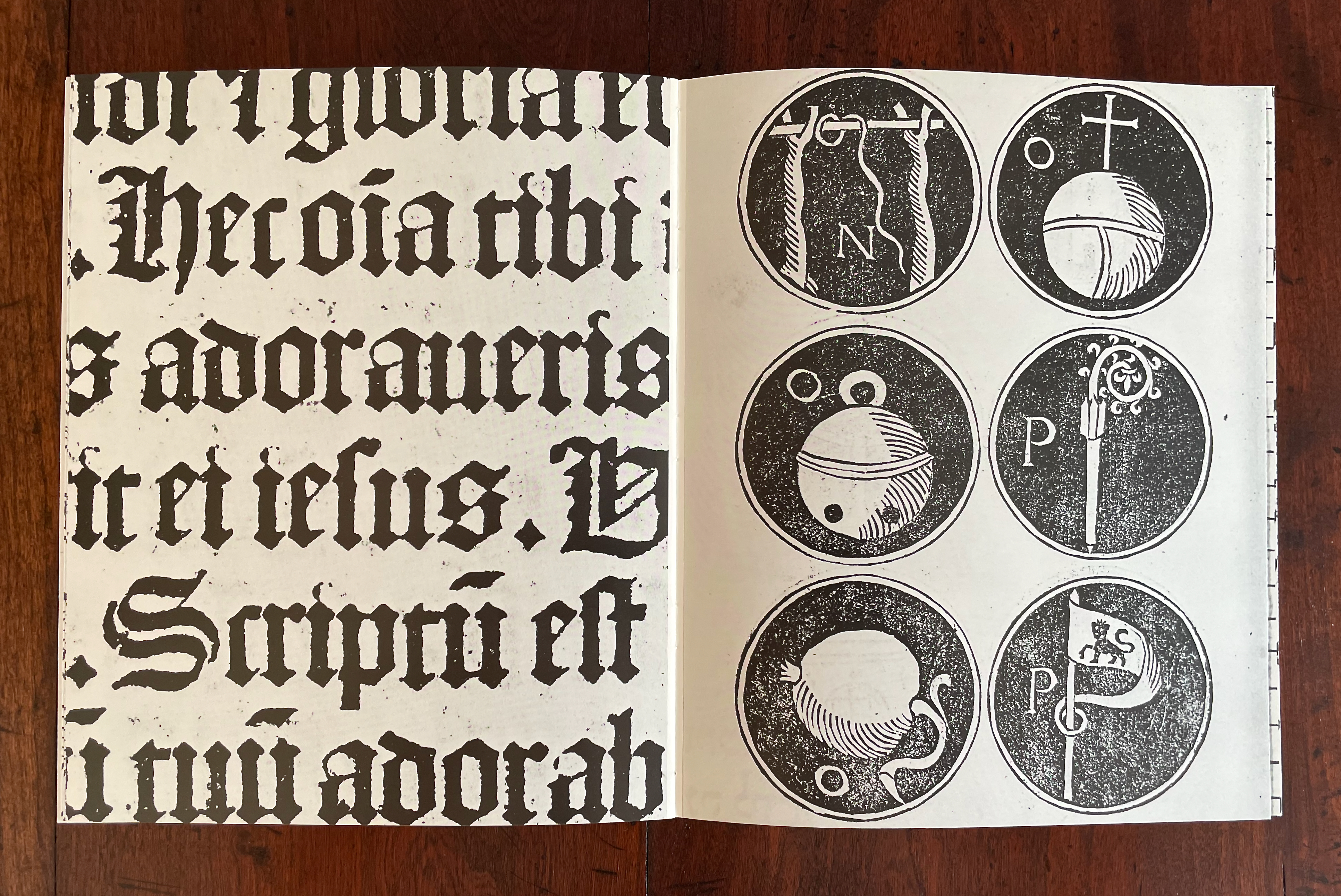 A spread showcasing a page with Gothic-style text on the left and six circular illustrations on the right, depicting various symbols and letters.