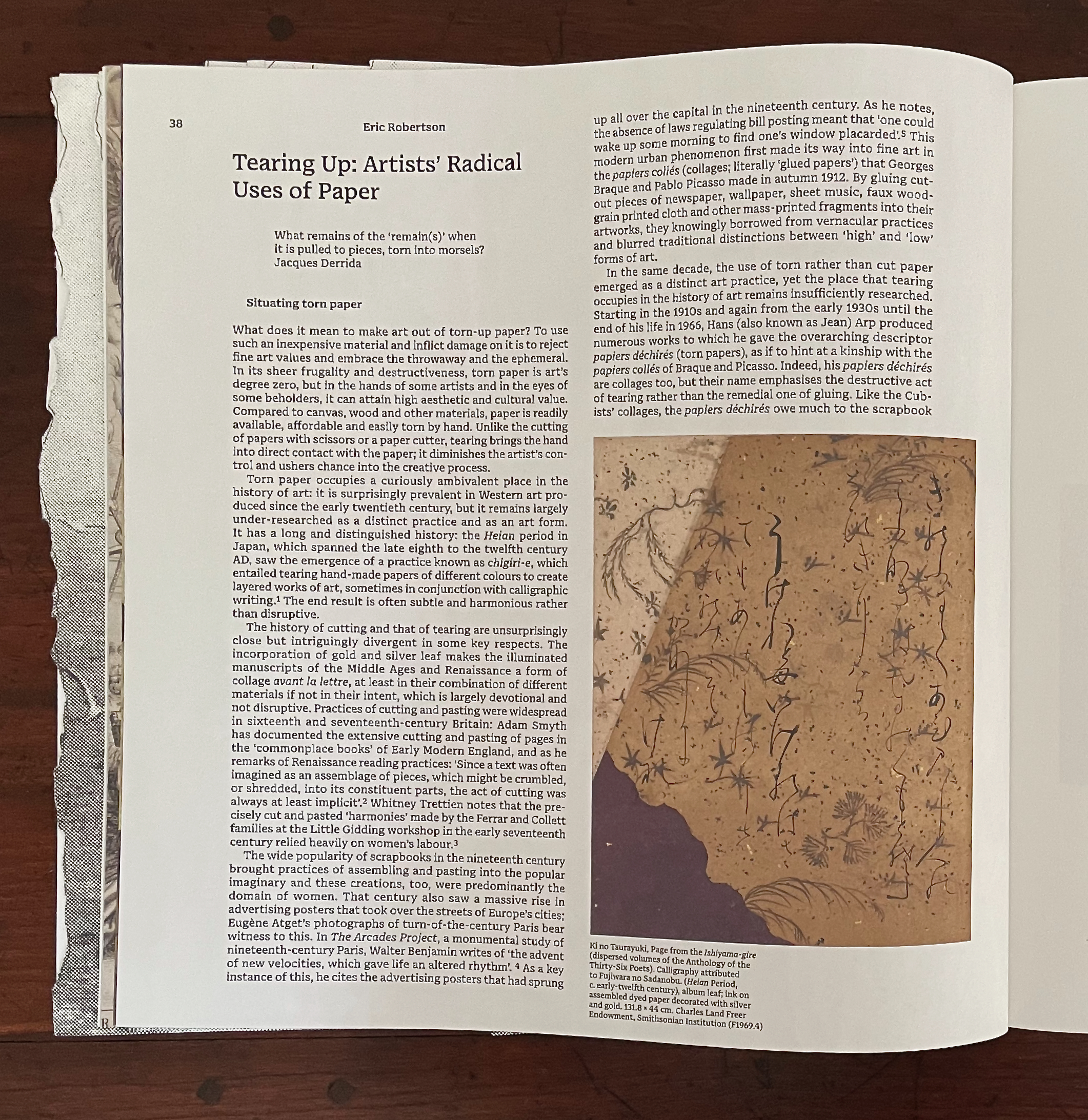 An open book page featuring an article titled 'Tearing Up: Artists' Radical Uses of Paper' by Eric Robertson. The left side contains text discussing the use of torn paper in art, while the right side features an image of an artwork with intricate calligraphy and designs on aged paper, highlighting the aesthetic of torn paper.