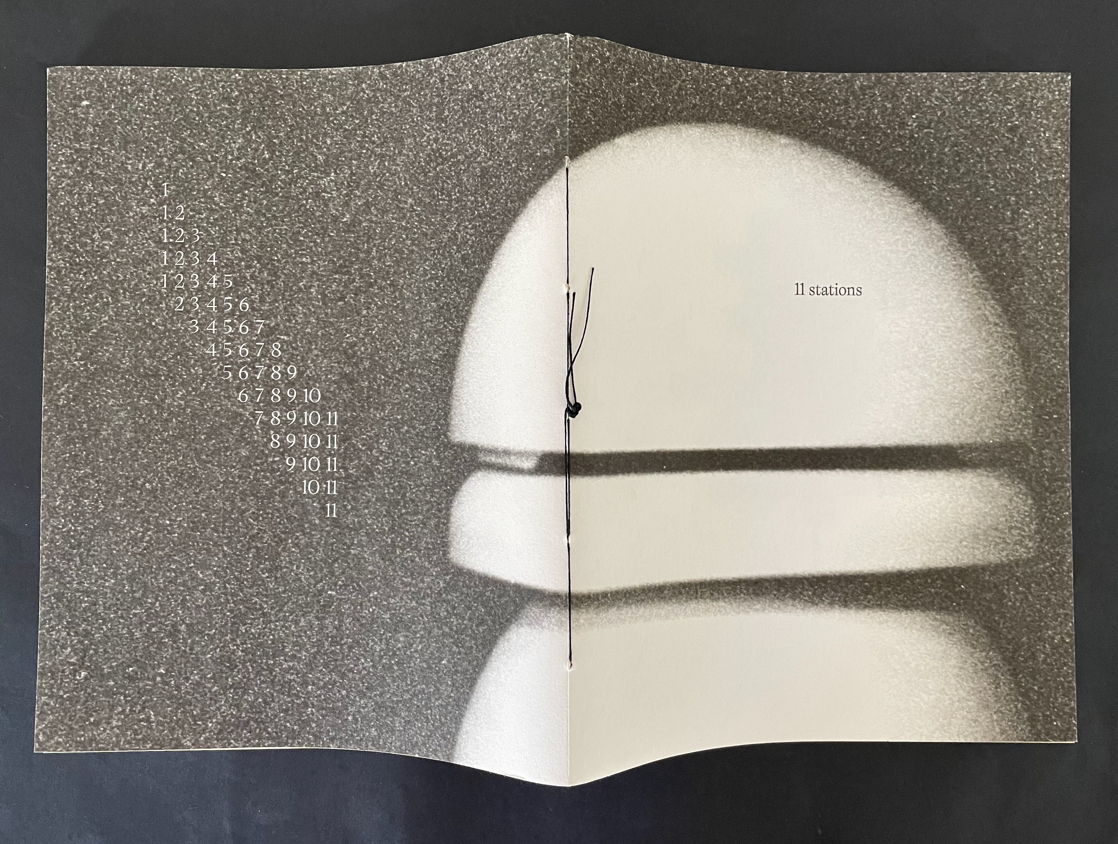 Open book with a textured gray background, displaying numerals in a vertical arrangement on the left side and the title '11 stations' on the right.