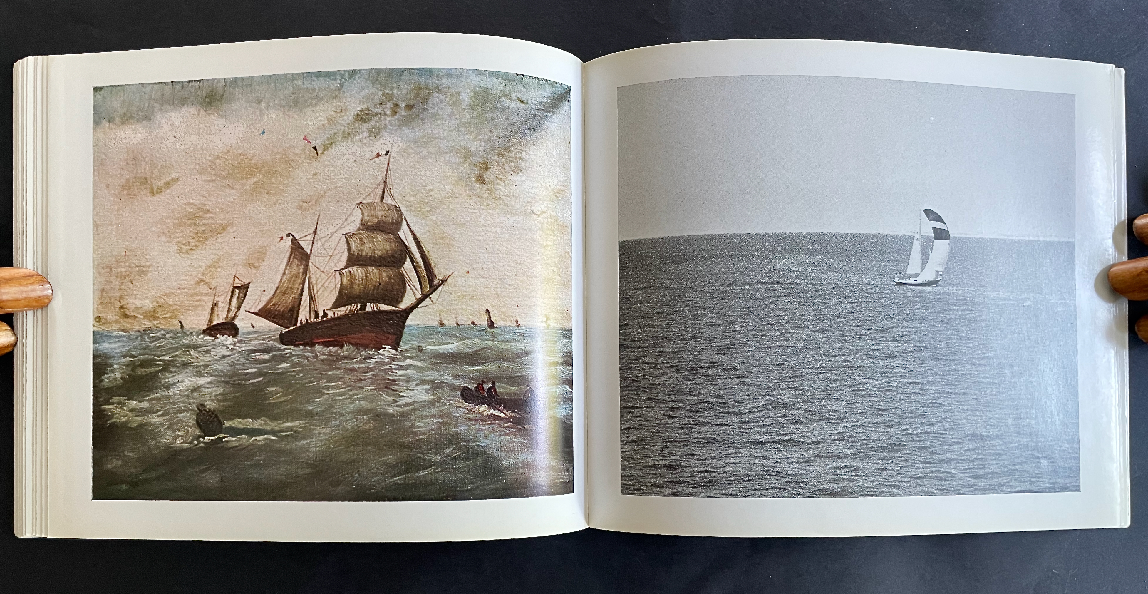 A book opened to two pages, featuring a painted scene of historic sailing ships on the left and a black-and-white photo of a sailboat on the right.
