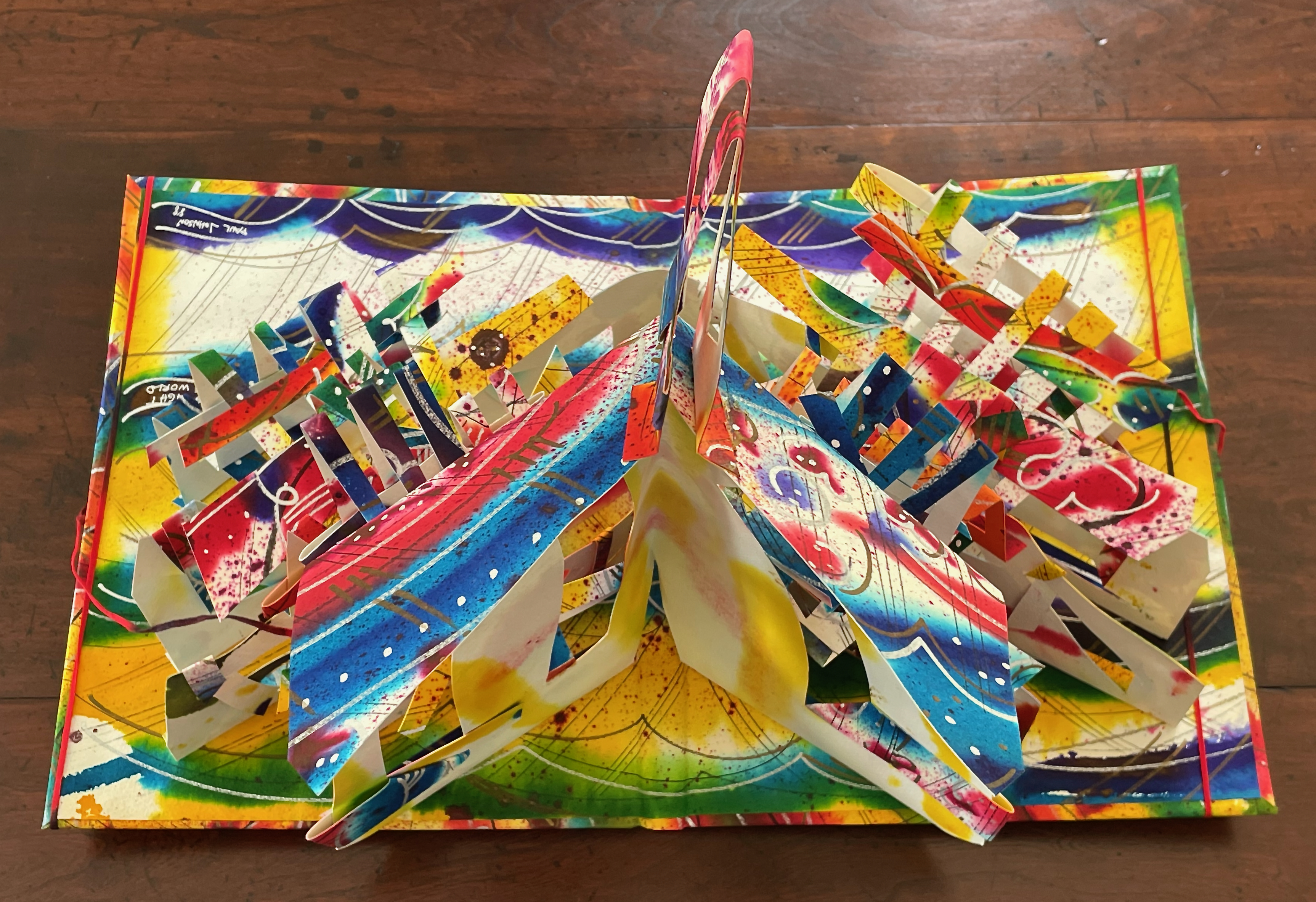 A colorful pop-up book with intricate paper structures featuring vibrant designs and patterns.