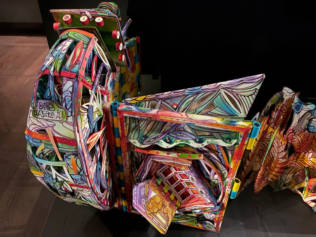 A colorful, intricately designed paper sculpture resembling a book with vibrant patterns and decorations.