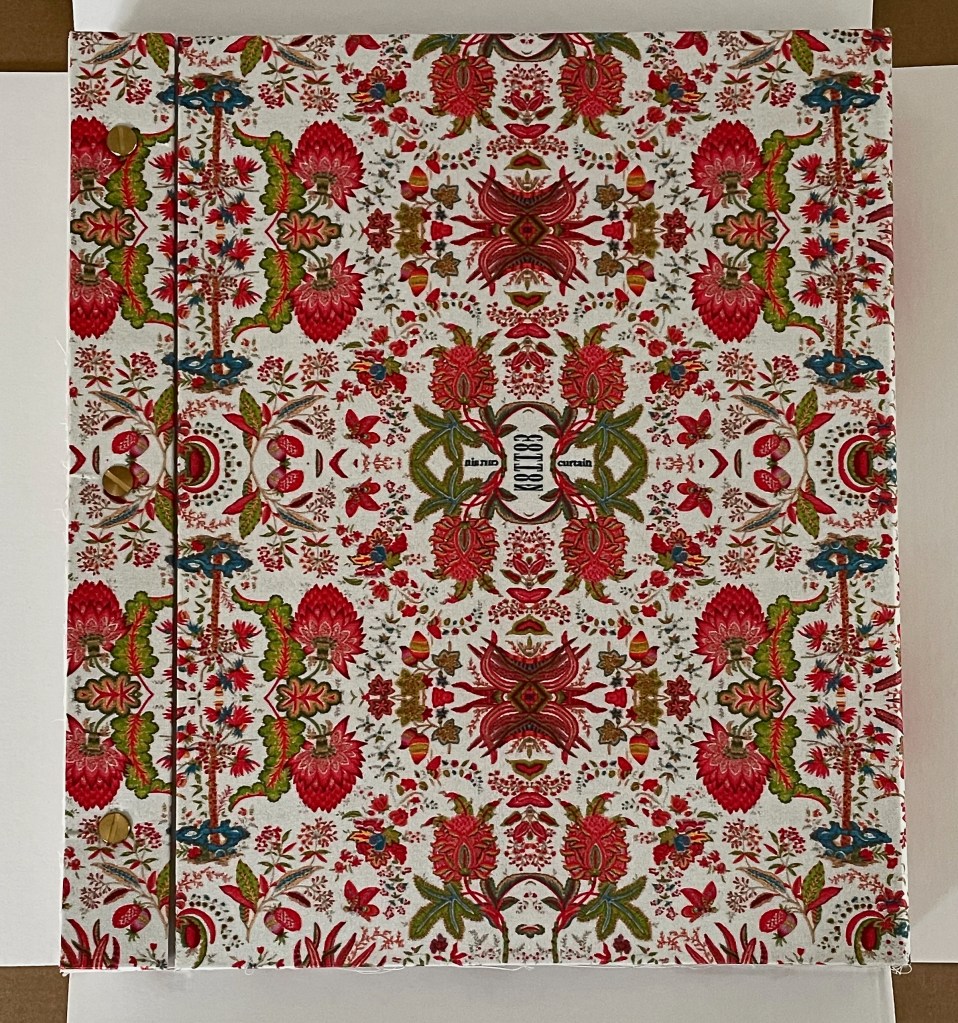 A decorative fabric cover featuring a vibrant floral pattern in red, green, and blue hues, with intricate designs on a white background.