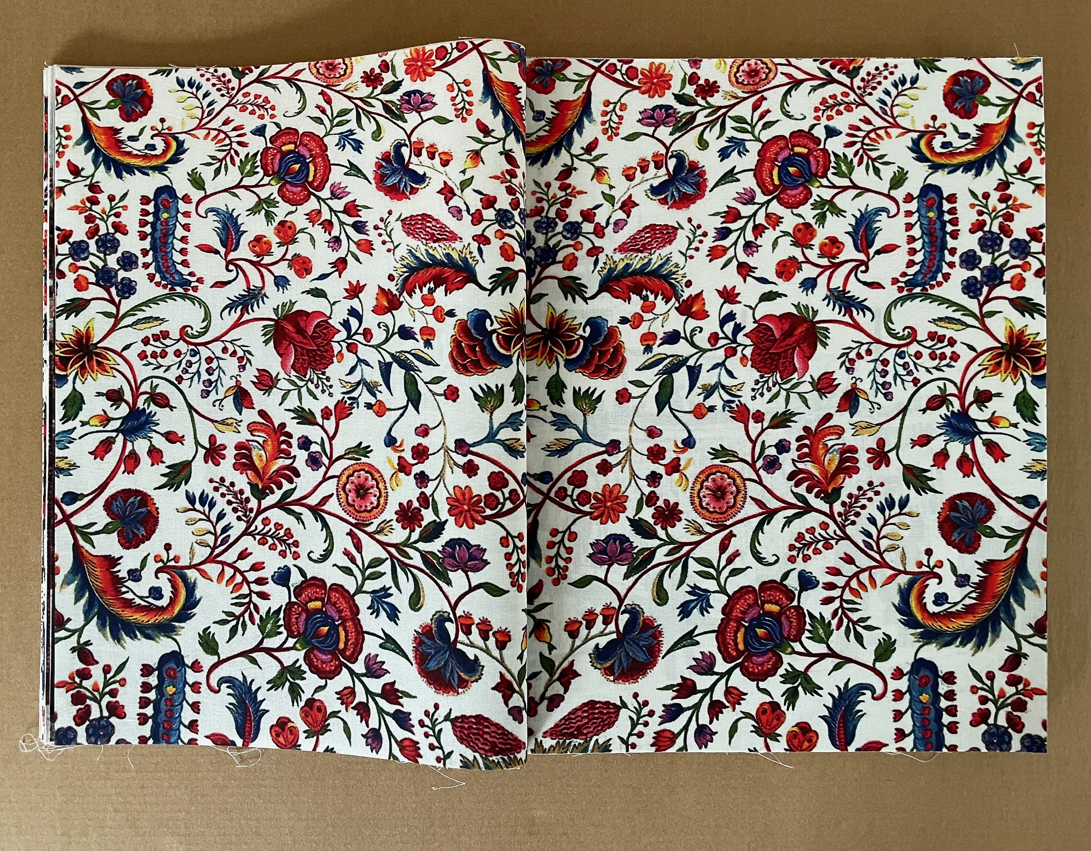 An open book displaying a vibrant floral pattern with various colorful flowers and leaves on a white background.