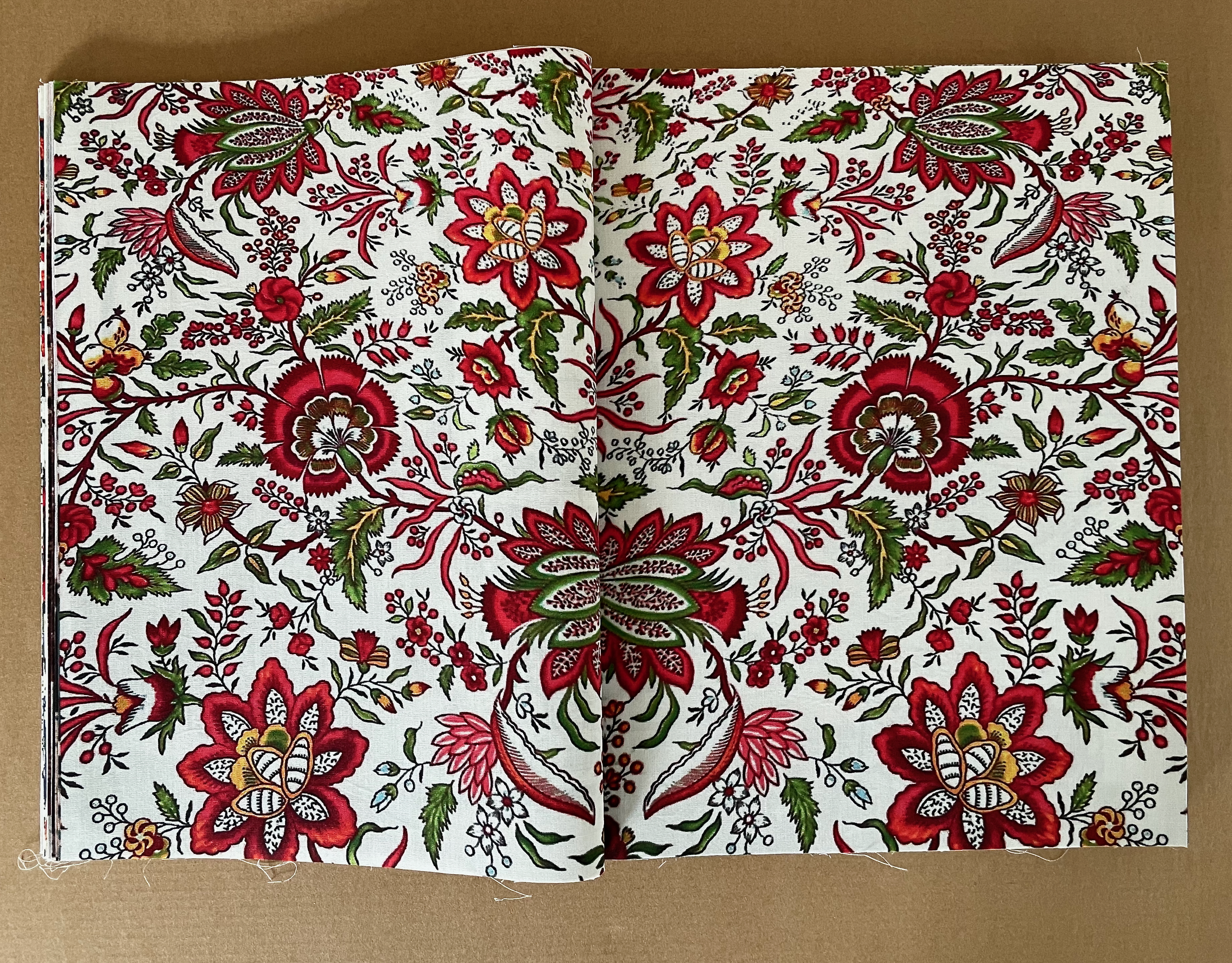 Opened book displaying a vibrant floral pattern with red, green, and white colors.