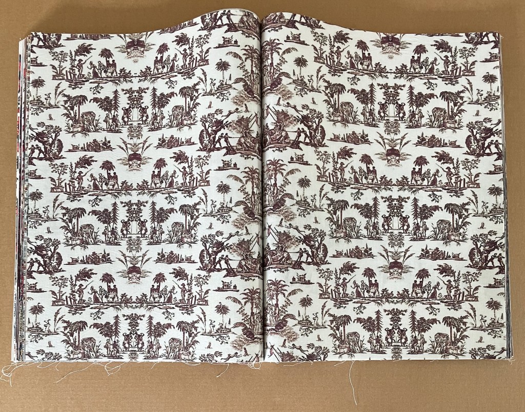 An open vintage book displaying a decorative fabric pattern with historical scenes, featuring multiple characters, animals, and vegetation in a rich reddish-brown color on a light background.