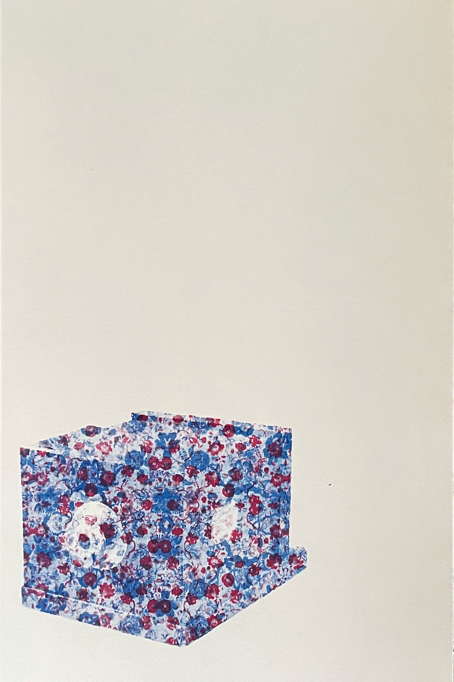 A three-dimensional object covered in a floral pattern featuring blue and red flowers, set against a plain background.