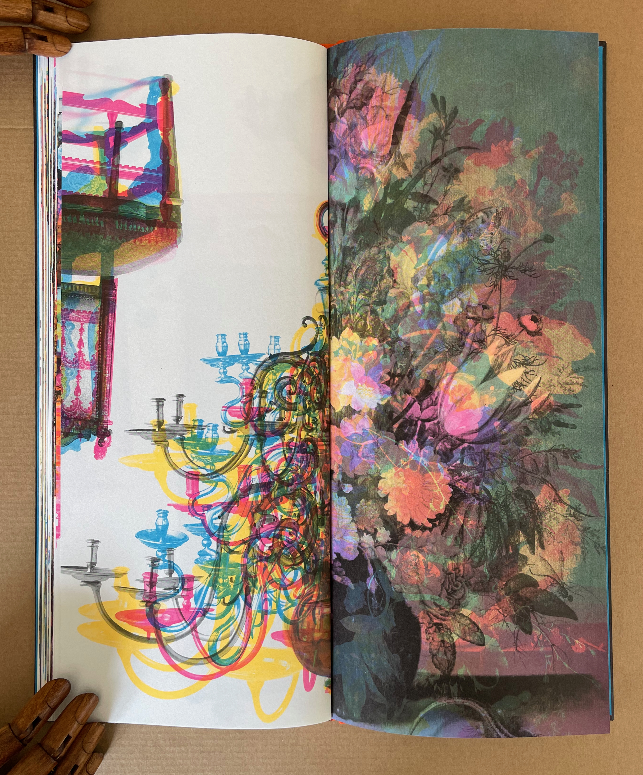 An open book featuring a colorful illustration of an ornate chandelier on the left page, with swirling, vibrant lines. The right page displays a lush, abstract floral arrangement in pastel colors.