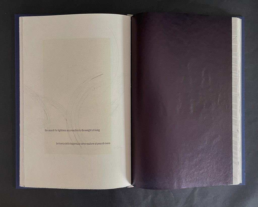 Open book spread featuring a light-colored page with the text 'the search for lightness as a reaction to the weight of living' and its Italian translation, on the left, against a darker page on the right.