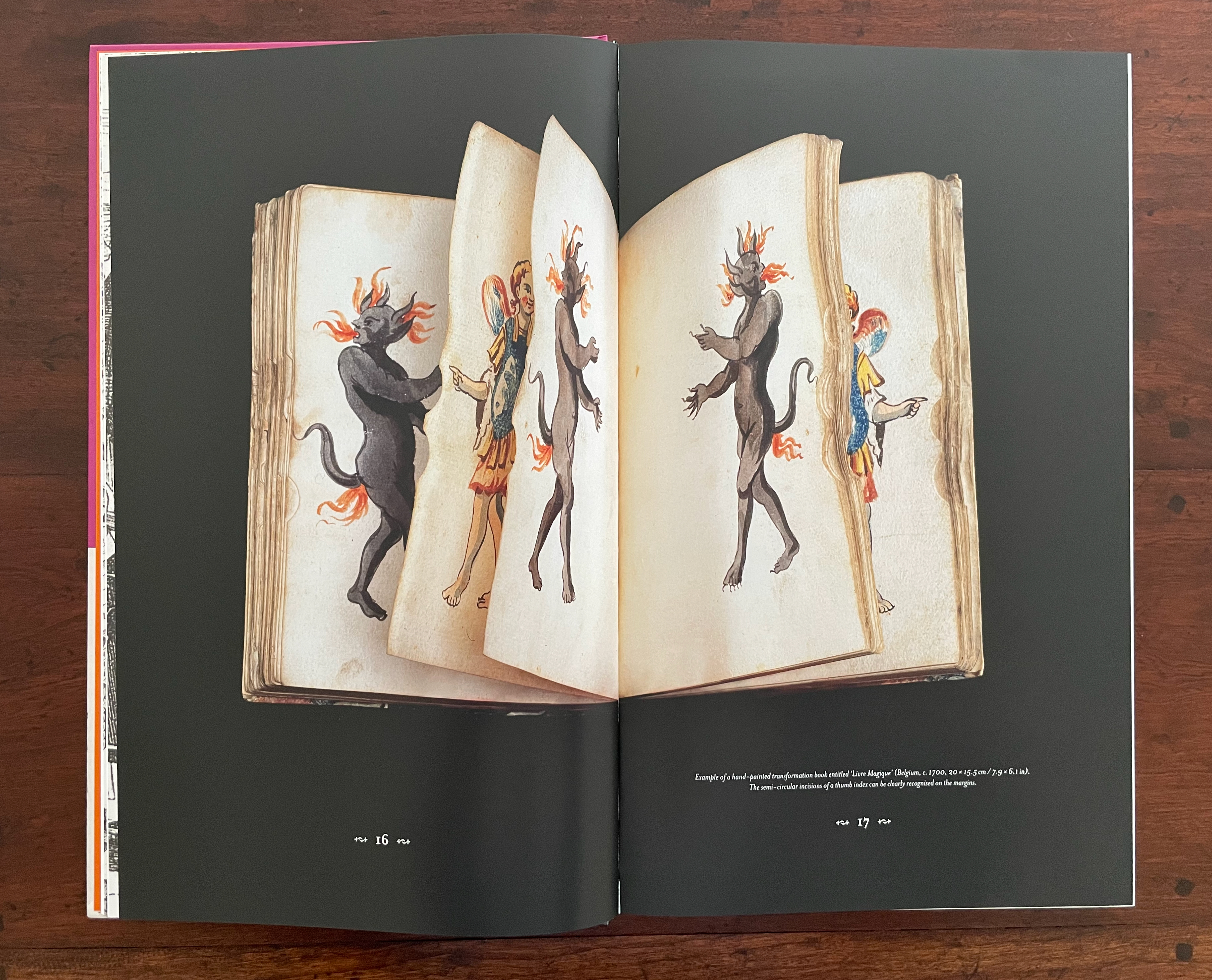 An open book displaying illustrated pages, featuring a figure wearing armor alongside two dark, horned creatures with fiery hair.