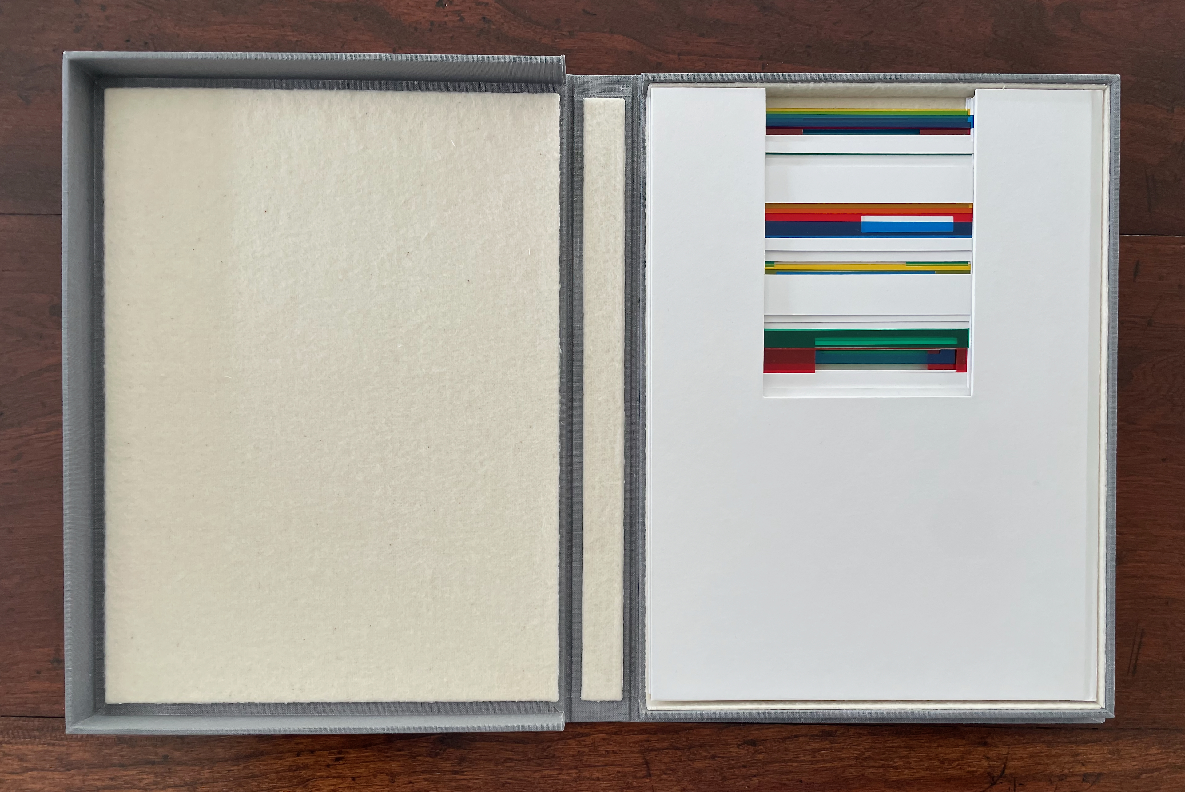 An open box displaying a white interior with colorful, transparent strips arranged within a rectangular cutout.