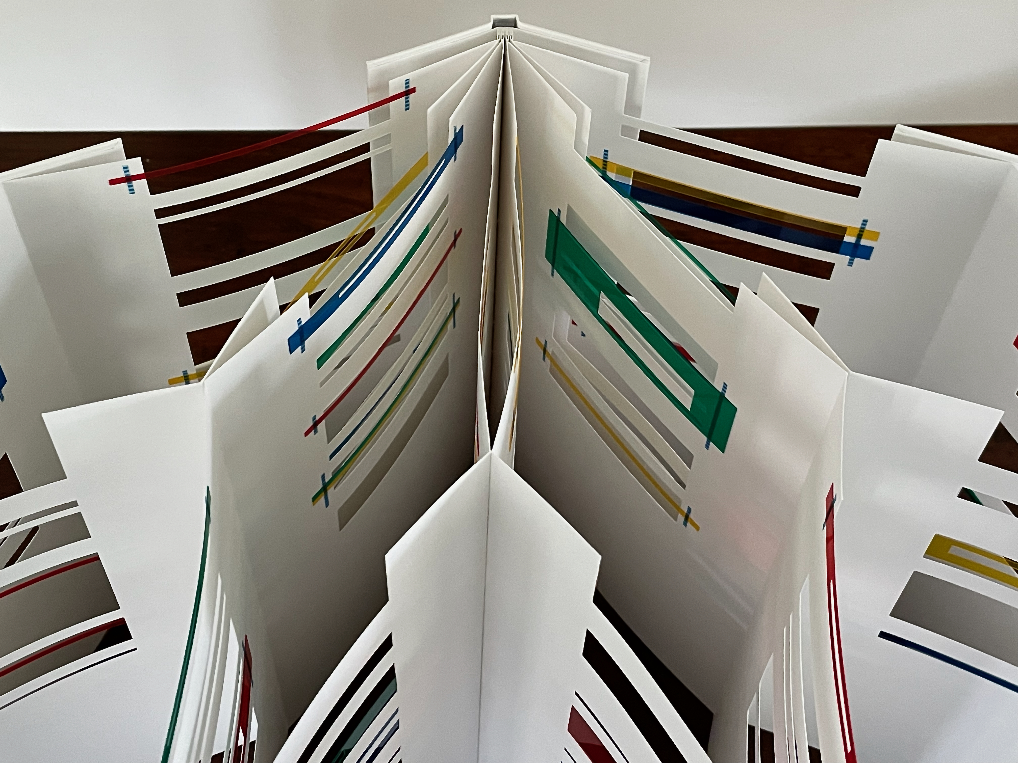 Open book showing colorful patterned pages with strips of colored paper.