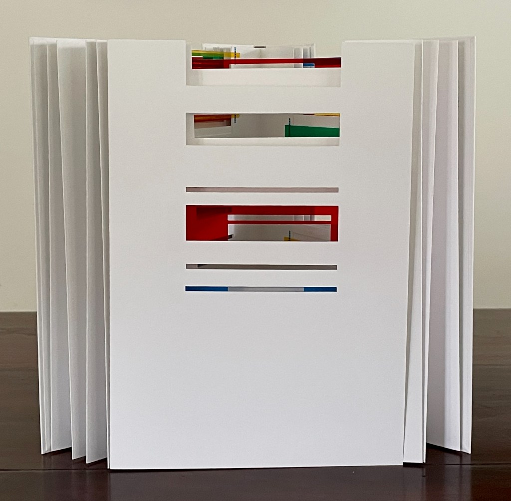 A white multi-section folder with colorful tabs visible in the openings, displayed on a wooden surface.