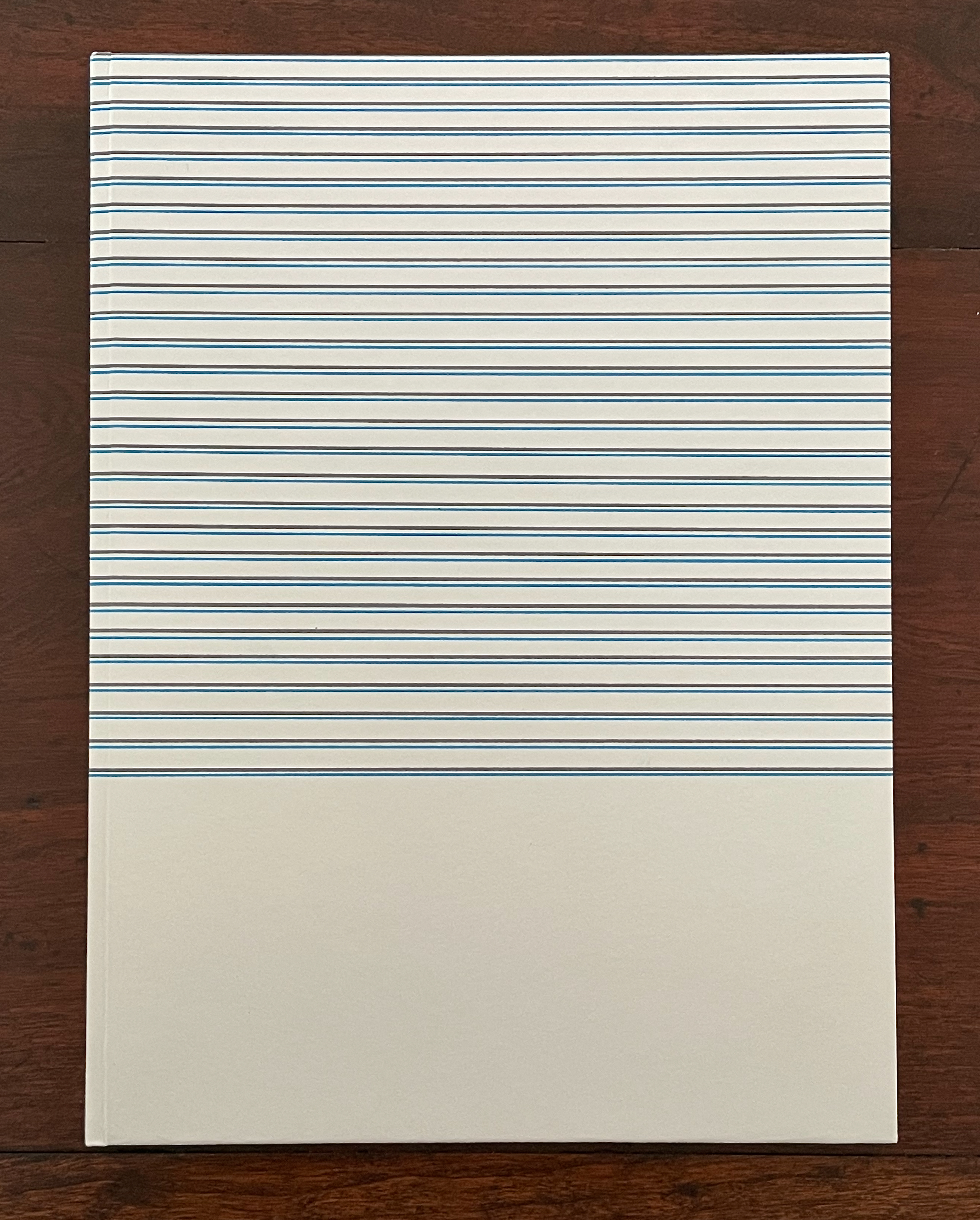A notebook with a cover featuring horizontal blue and white stripes, resting on a wooden surface.
