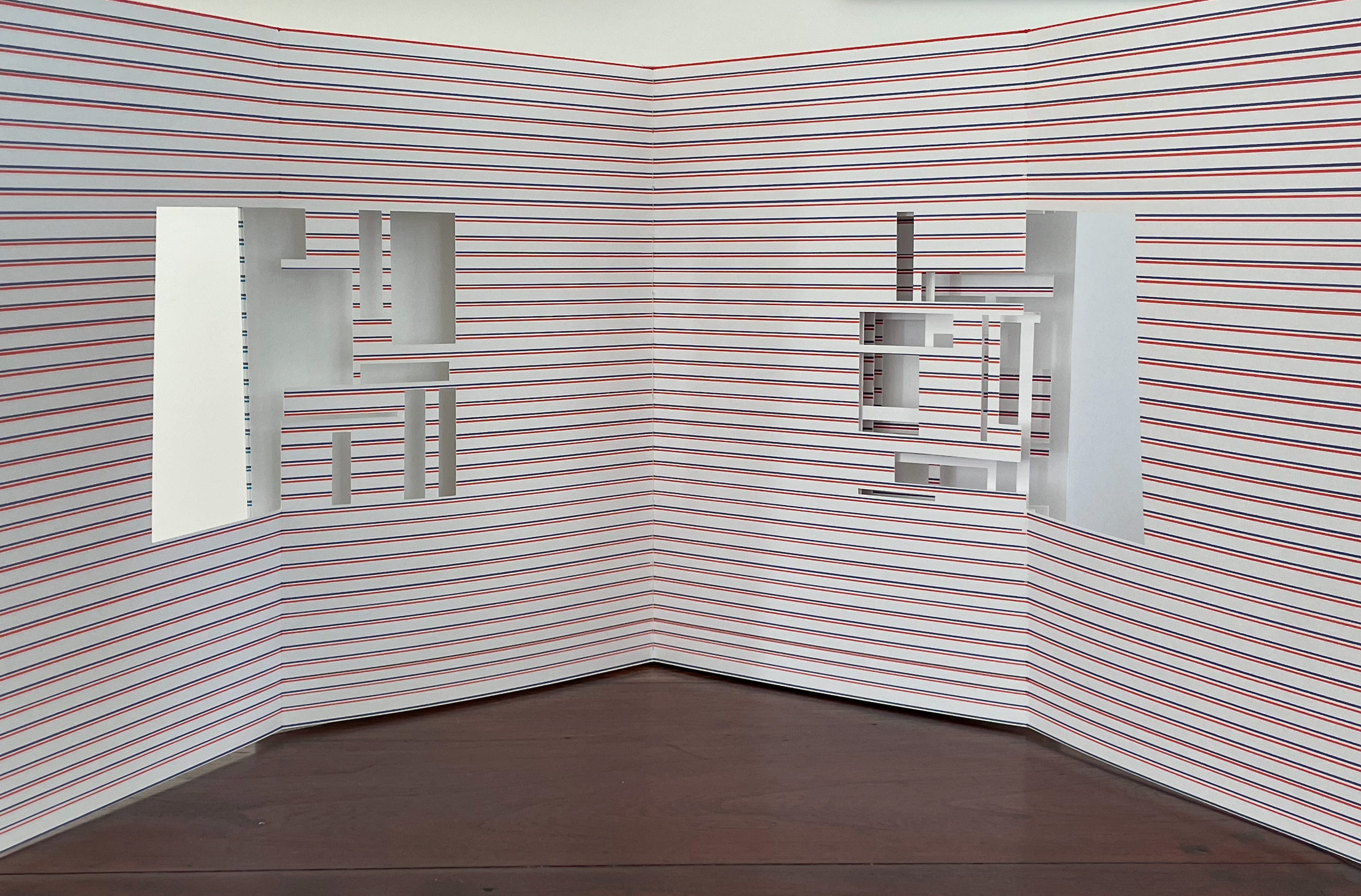 A white corner installation featuring cut-out geometric shapes against a striped background of red and white lines.