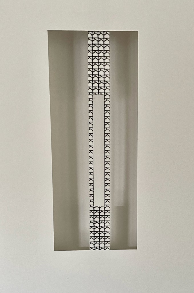 An abstract wall design featuring a central cutout with a pattern resembling interlocking shapes, set against a plain white backdrop.