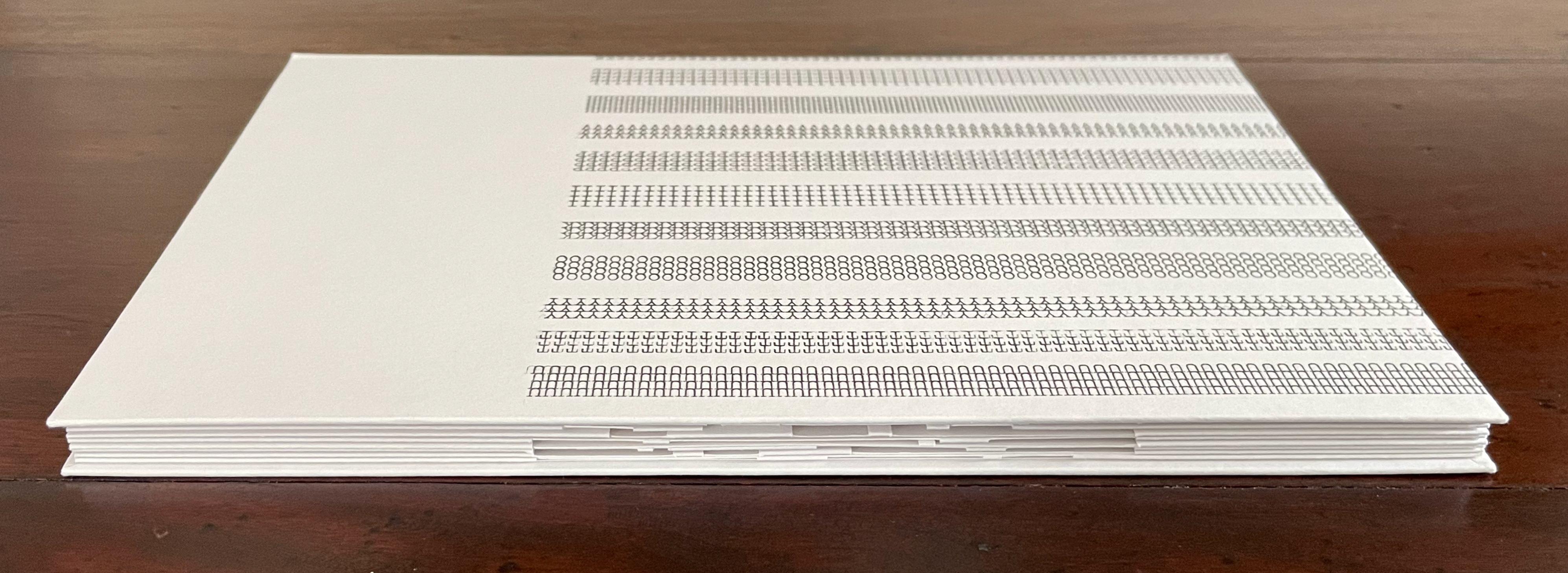 A closed book with a textured cover, featuring printed patterns in black and white.