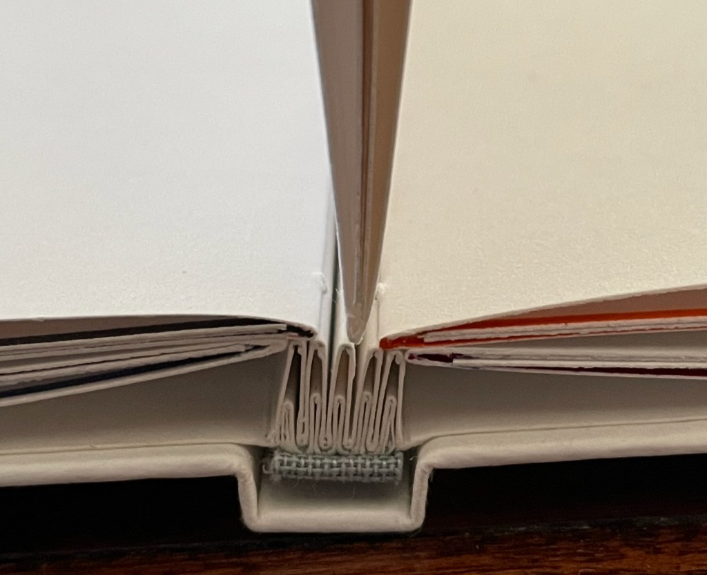 Close-up view of the spine of a book with visible stitching and pages, showcasing the binding mechanism.
