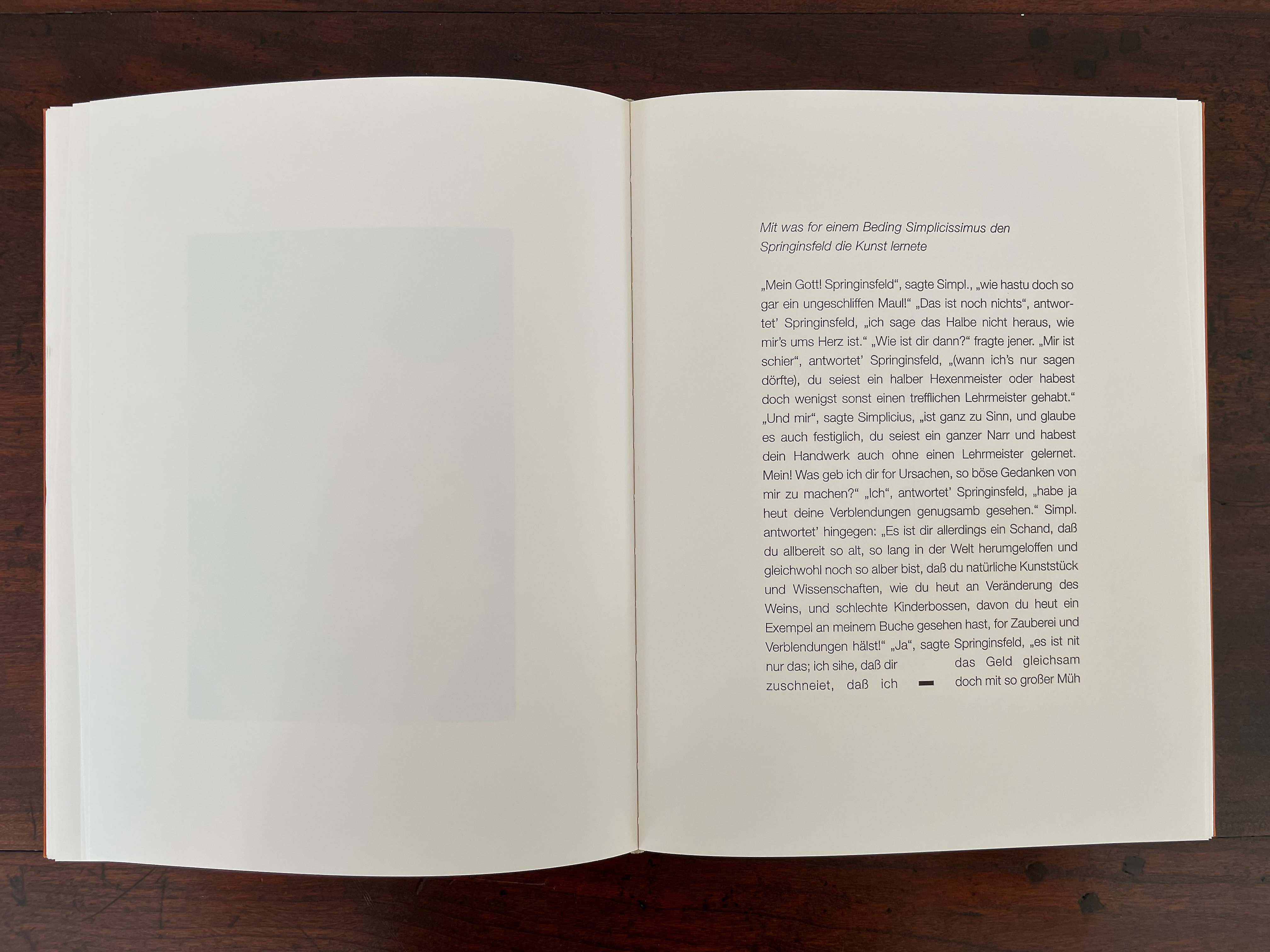 Open book on a wooden table, displaying text in German on the right page with a blank section on the left page.