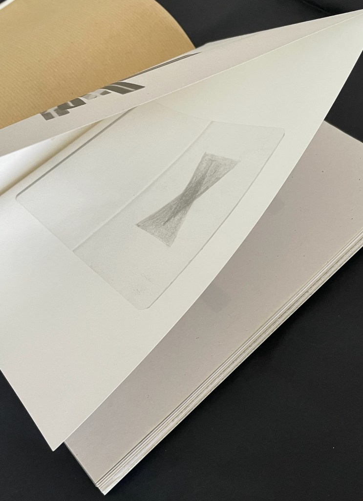 A close-up of an open book displaying a sketch of an hourglass shape on a page with a visible cut-out.