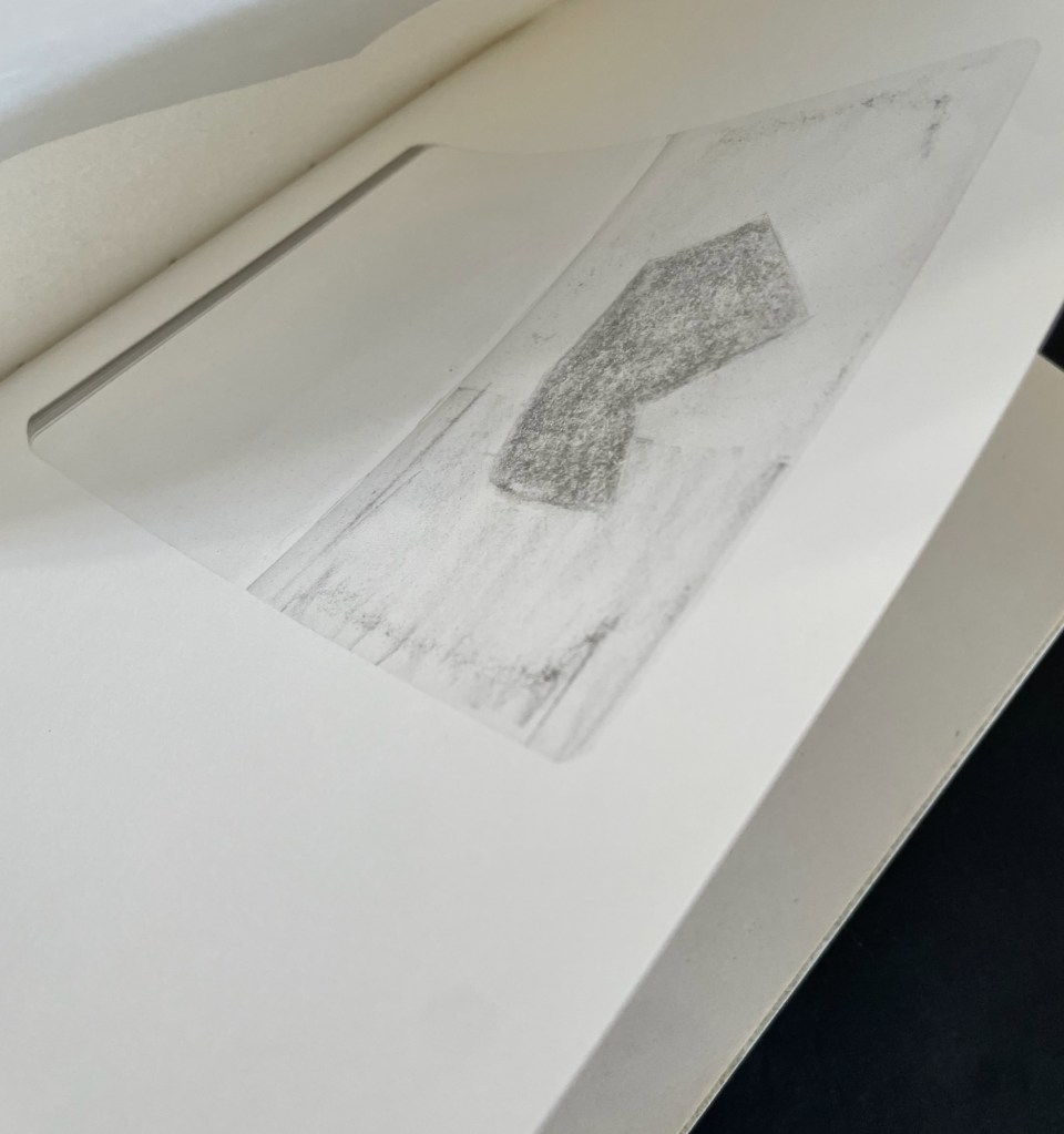 A close-up of a sketchbook page featuring a pencil sketch of a geometric shape, with the inner edge revealing another page.