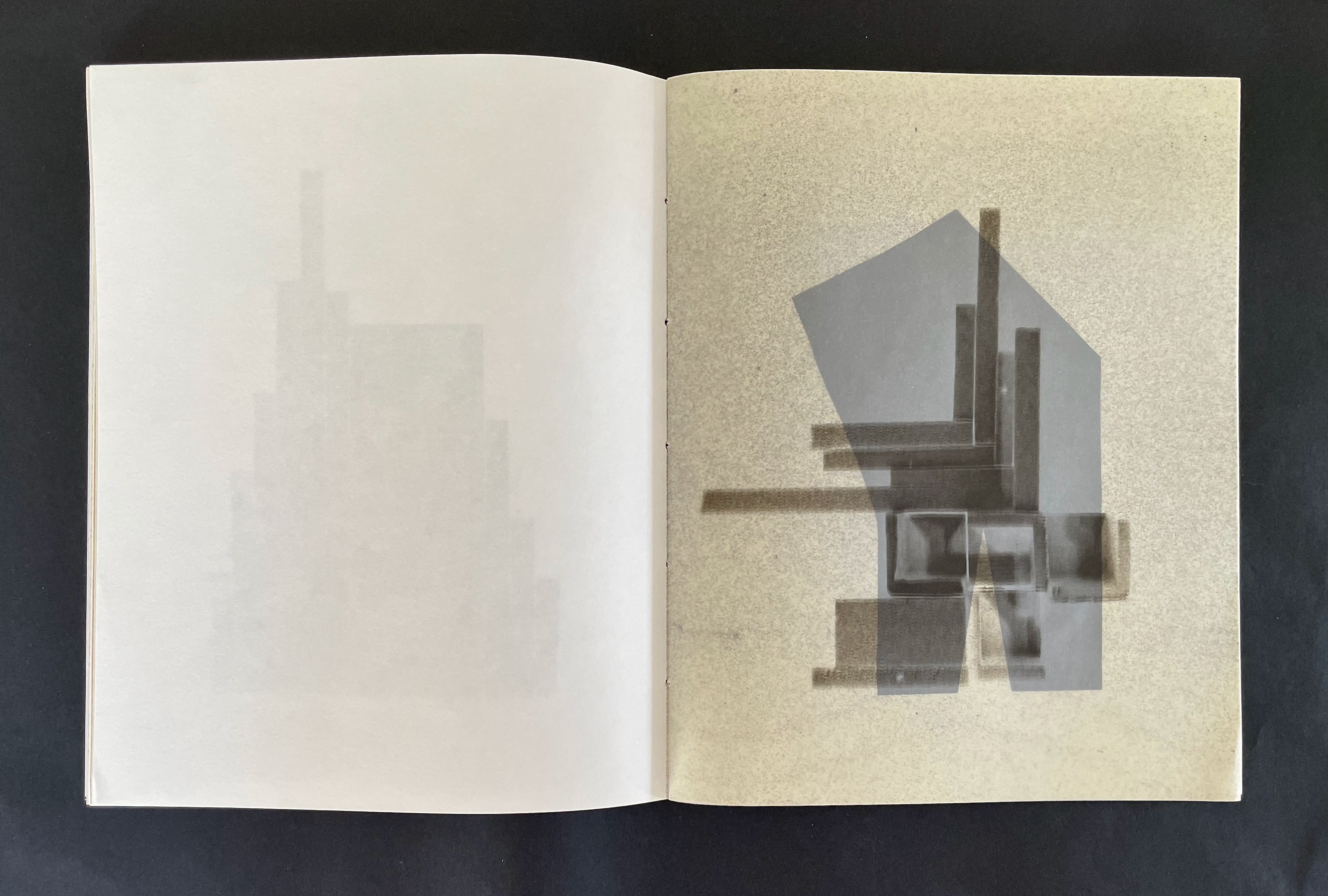 An open book displaying abstract geometric shapes and shadows on textured pages.