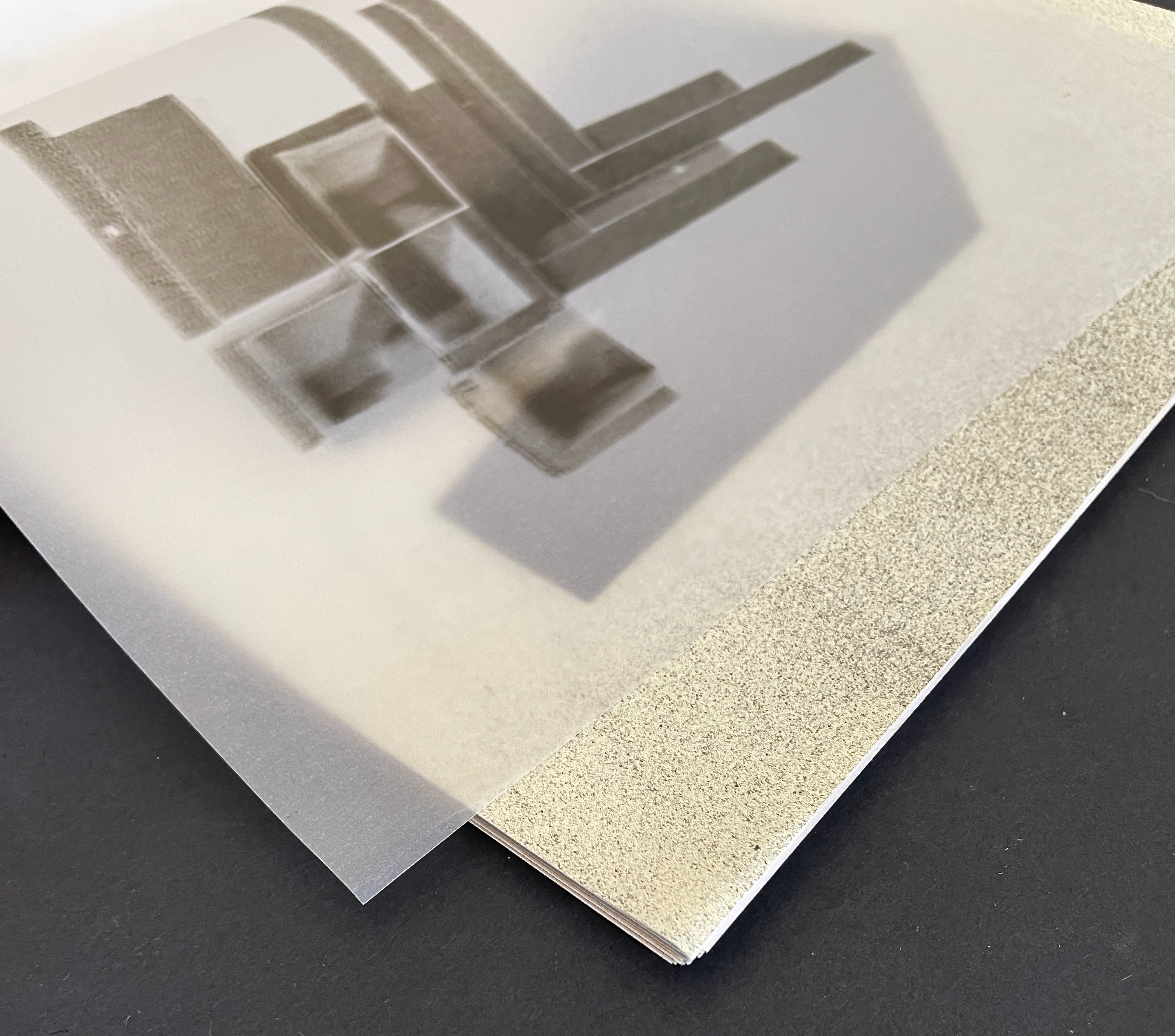 Close-up of a frosted sheet of transparent material overlaying a textured surface, with geometric shapes partially visible beneath.