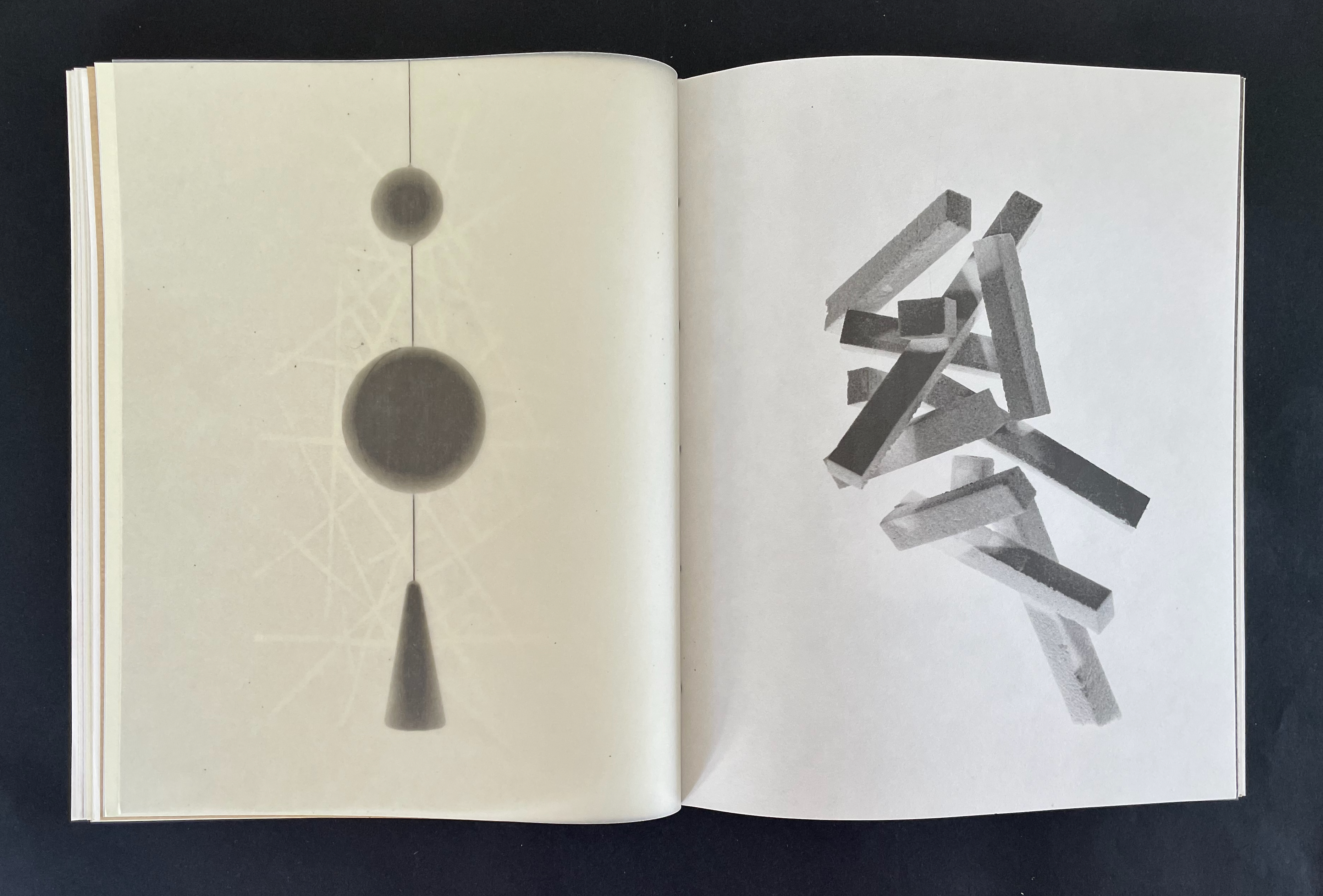 Open book page featuring abstract geometric shapes: a vertical arrangement of circles and a cone on the left, and scattered rectangular forms on the right.