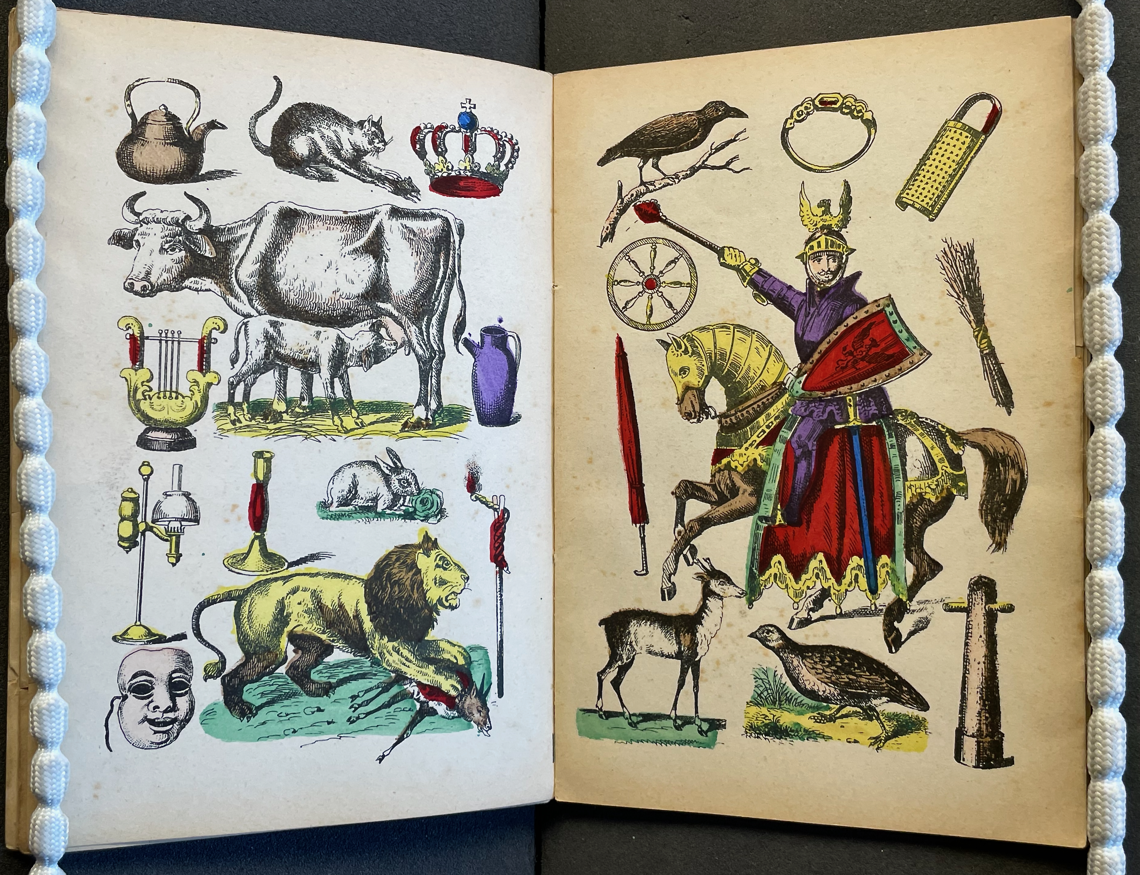 An illustrated page featuring various colorful drawings, including a kettle, a cat, a crown, a cow with a calf, a hare, a lion, a horseman in armor on a horse, a bird, and other objects like a lyre and a candle holder.